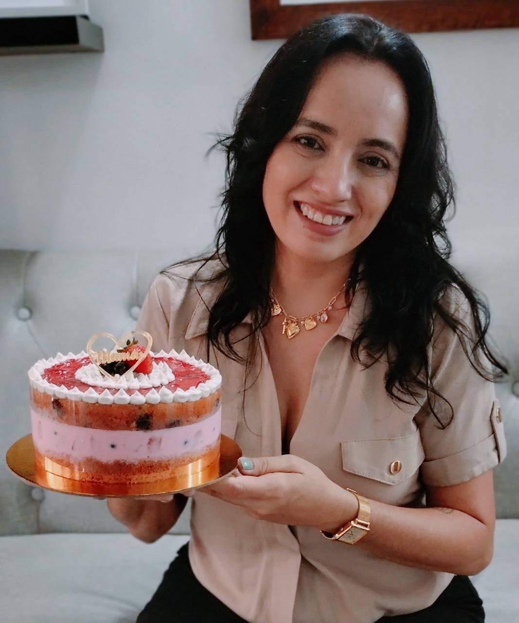 a woman holding a cake with a strawberry cream frosting