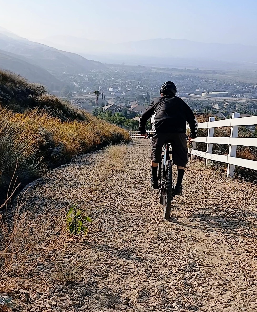 Mountain biker riding downhill on a loose gravel trail, focused on balance and control.