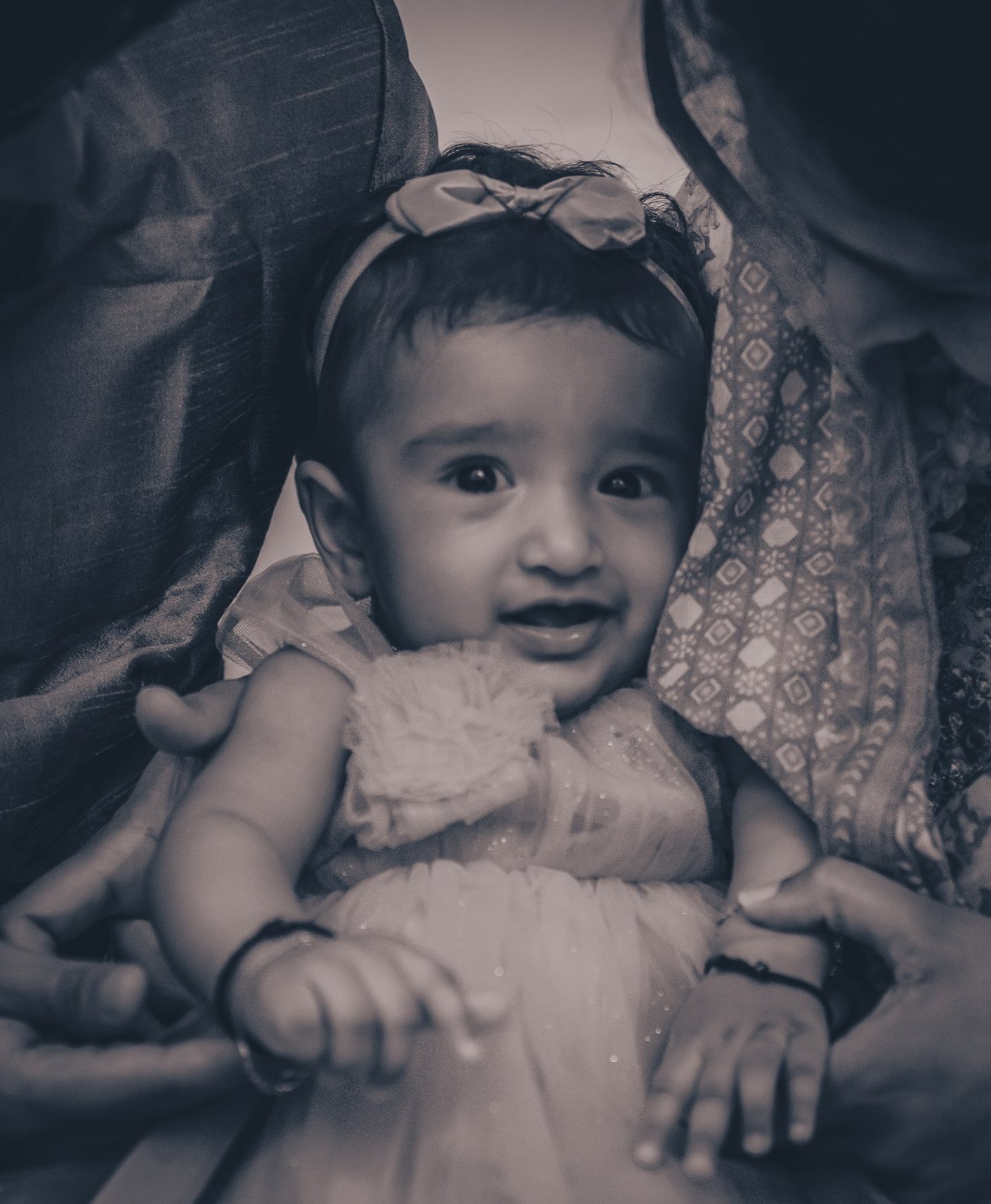 A black and white portrait of a baby girl wearing a white dress and bow headband, photographed by Me