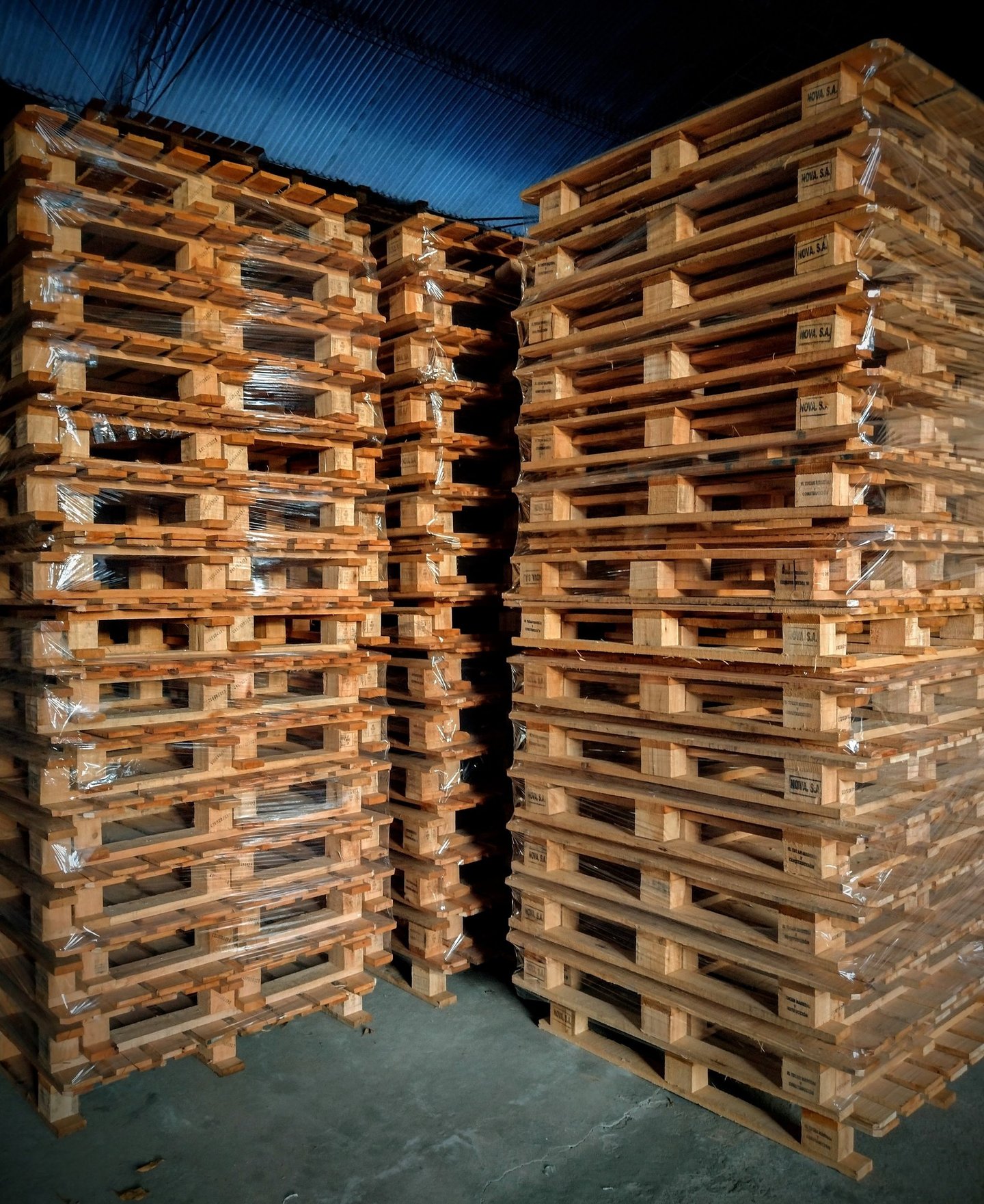 Grandes pilas de palés de madera tratada térmicamente, envueltos en plástico.