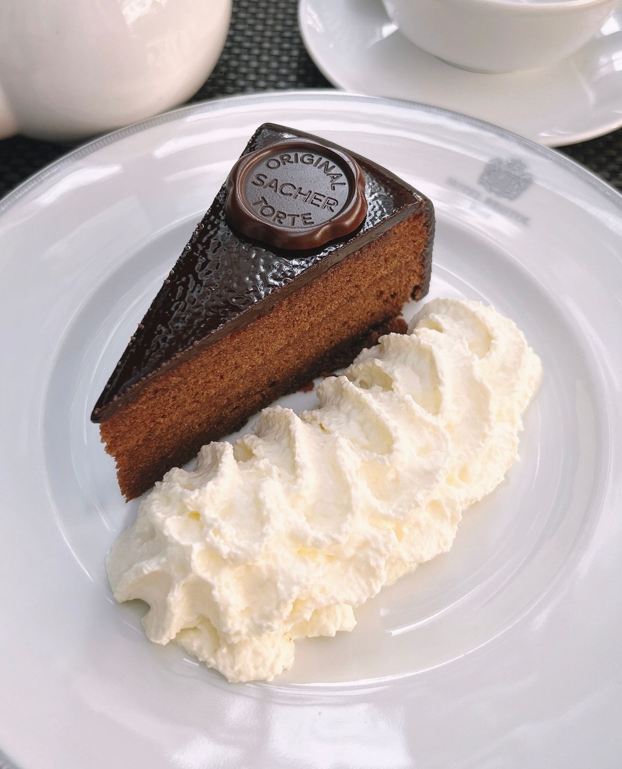 Porción de la auténtica tarta Sacher con su brillante cobertura y sello oficial de chocolate