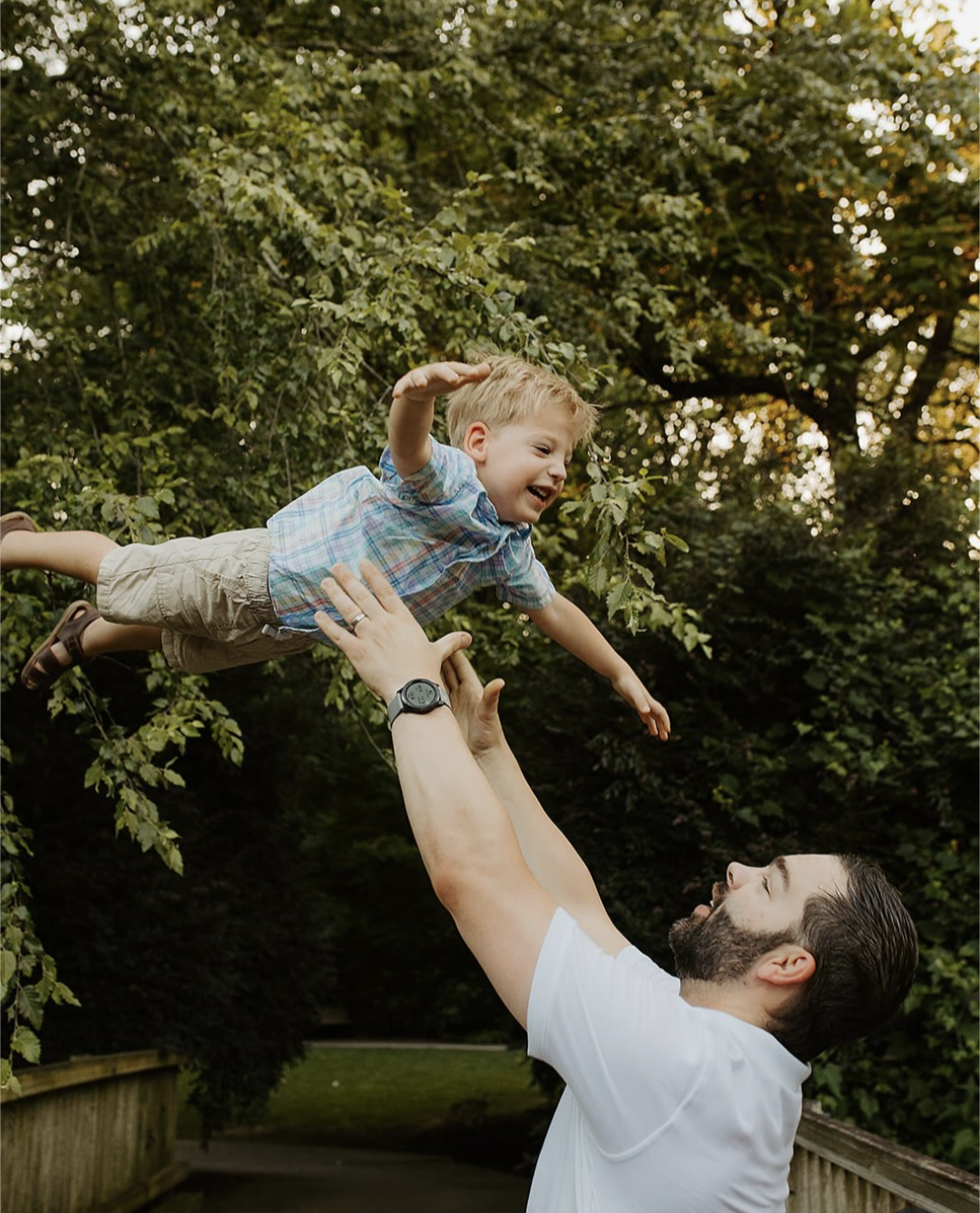 Brian Hess, owner, throwing son up in the air with trees in the background