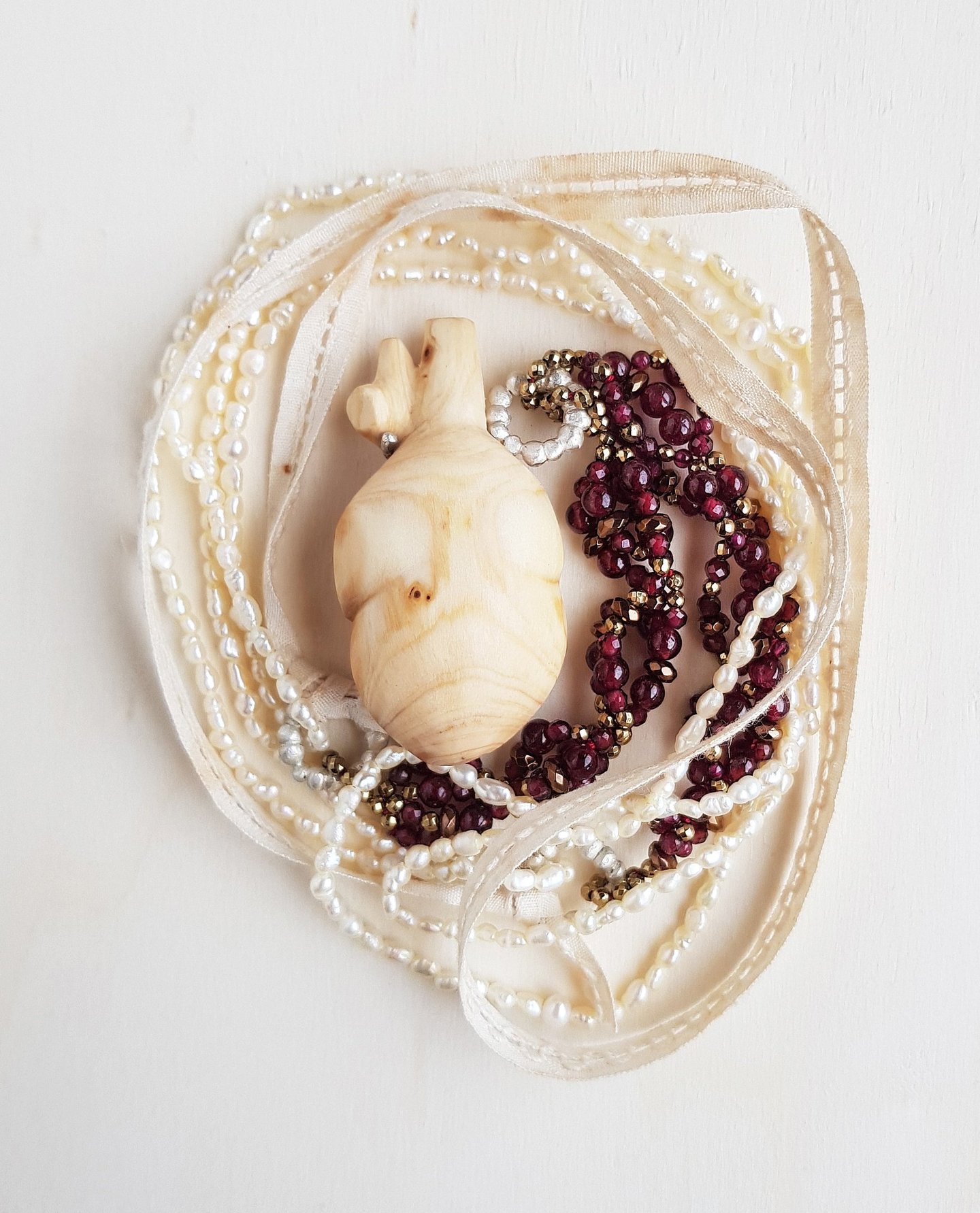 Wooden heart withe accompanied by granates, hematites, pearls, silver and antique lace. Wearable Art