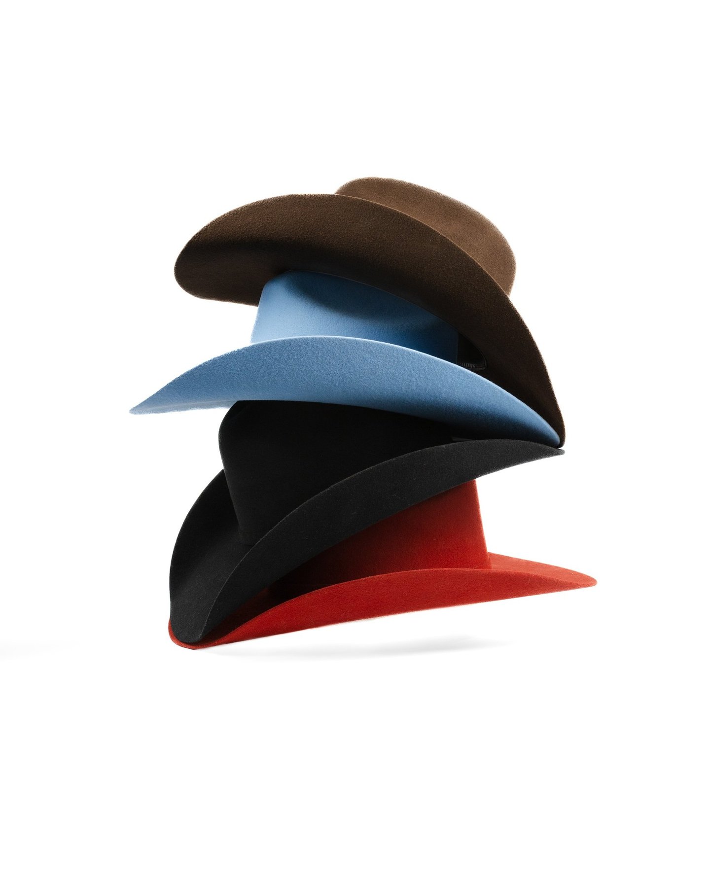 A stack of colorful wide-brimmed felt fedora hats in brown, light blue, black, and red.