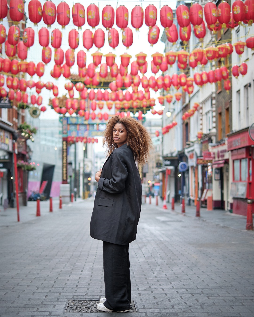 ensaio fotográfico urbano com mulher posando em rua decorada com lanternas orientais