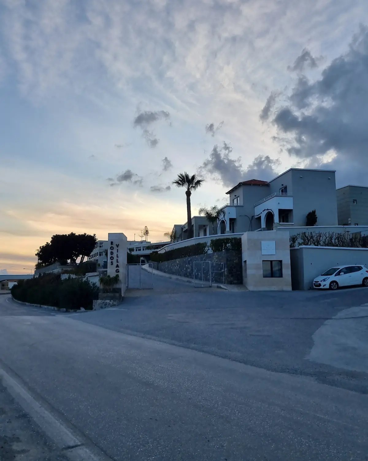 Luxury Rodos Village resort villas in Rhodes, Greece, during a scenic sunset with palm trees.