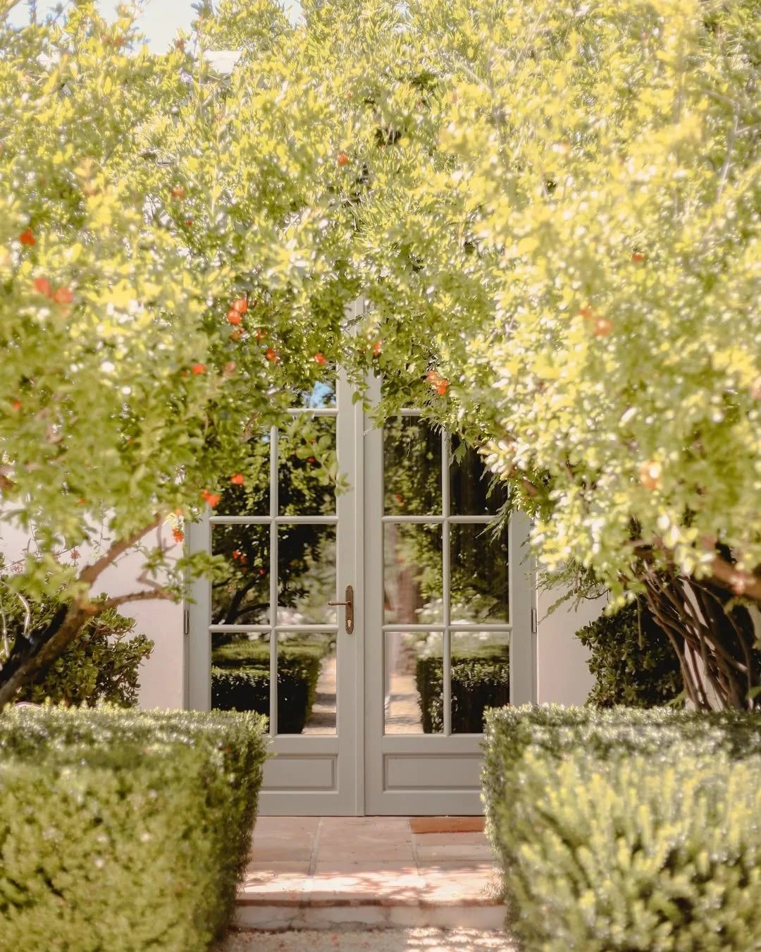 Garden entrance with glass doors framed by flowering trees