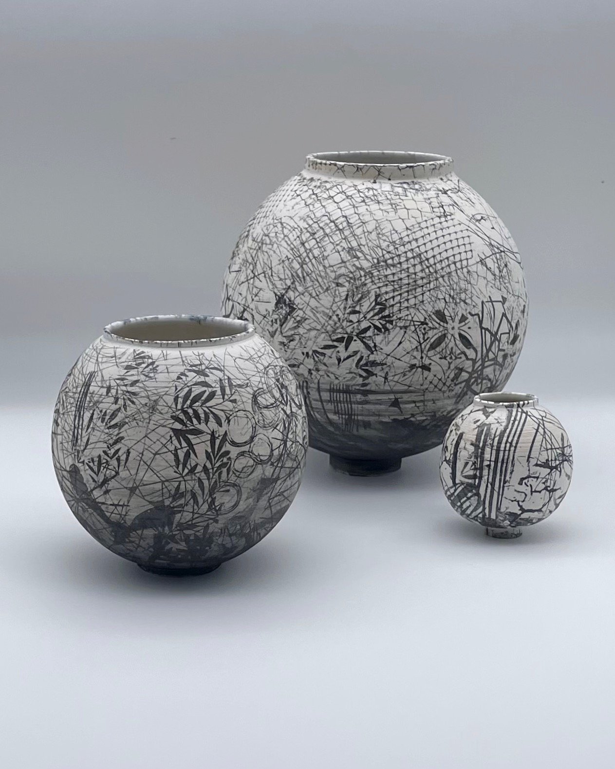 3 ceramic moon jars which are different sizes with abstract black and white pattern on the surface
