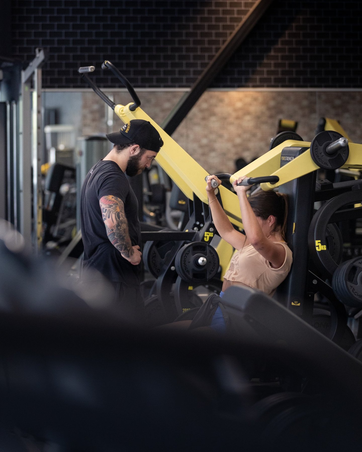 moi en train de coacher ma cliente emmie sur une shoulder press tecnogym