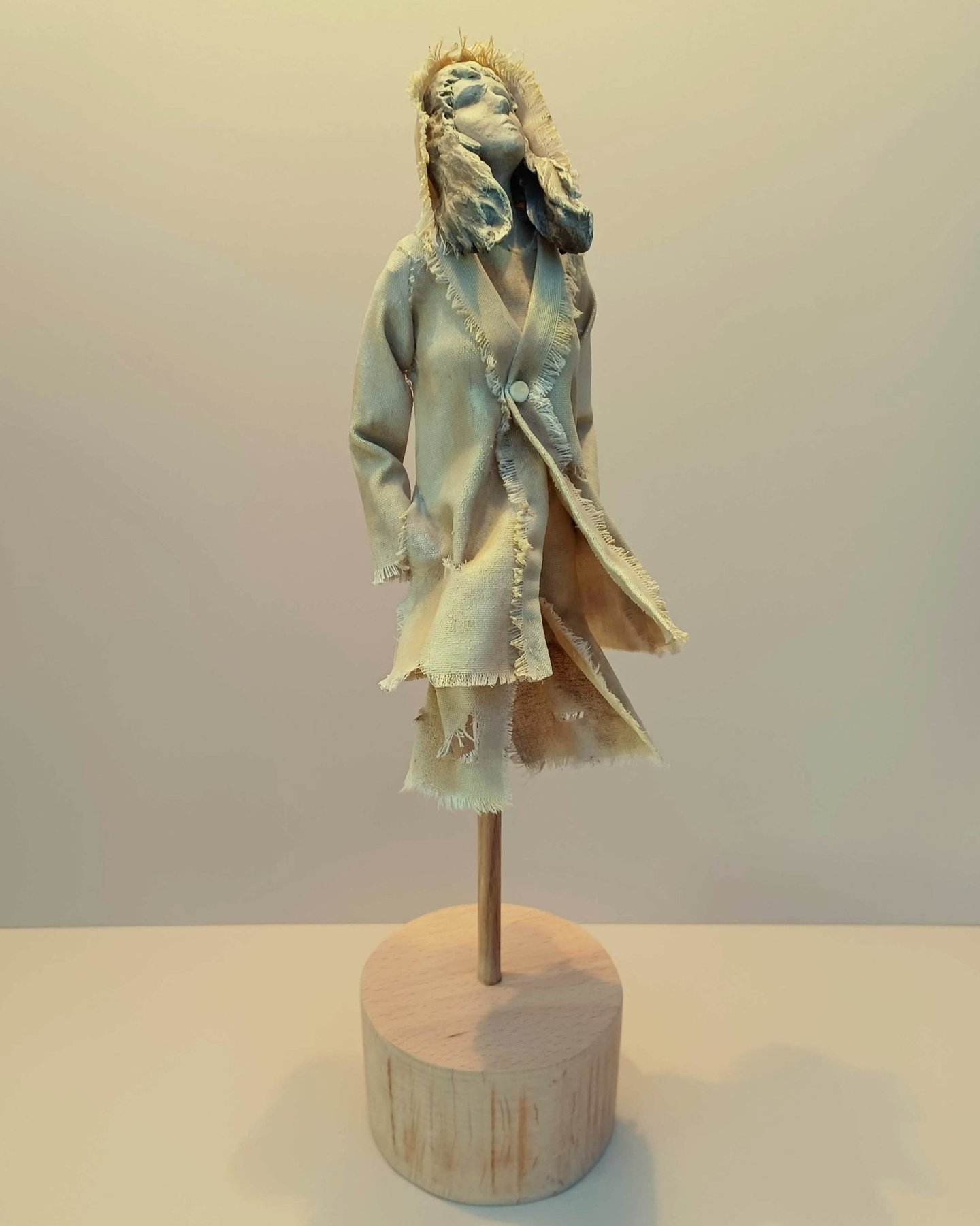 Clay and canvas sculpture of a female figure gazing upwards, wearing windswept, ragged clothes.