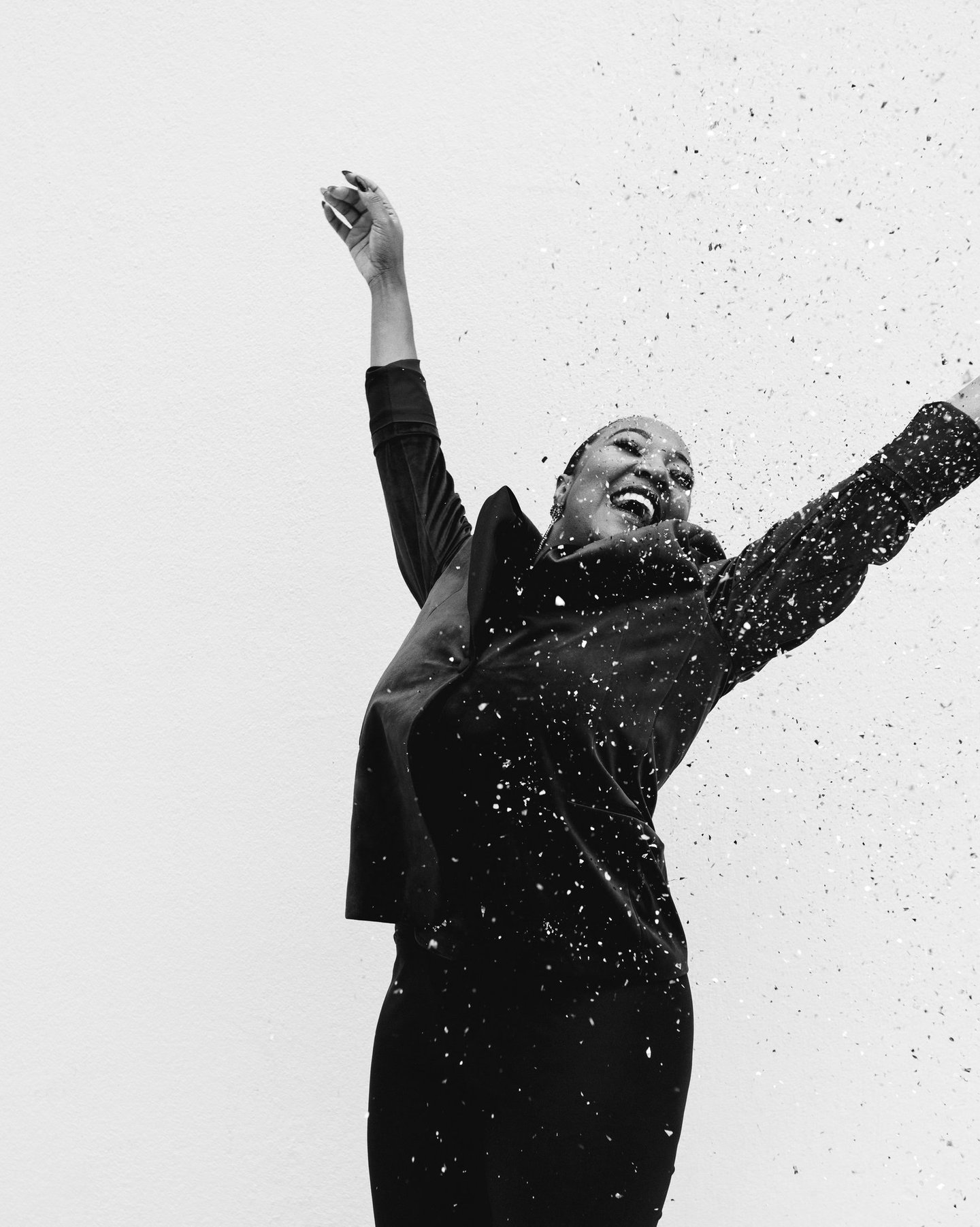 a woman in a black dress celebrating with confetti, black and white