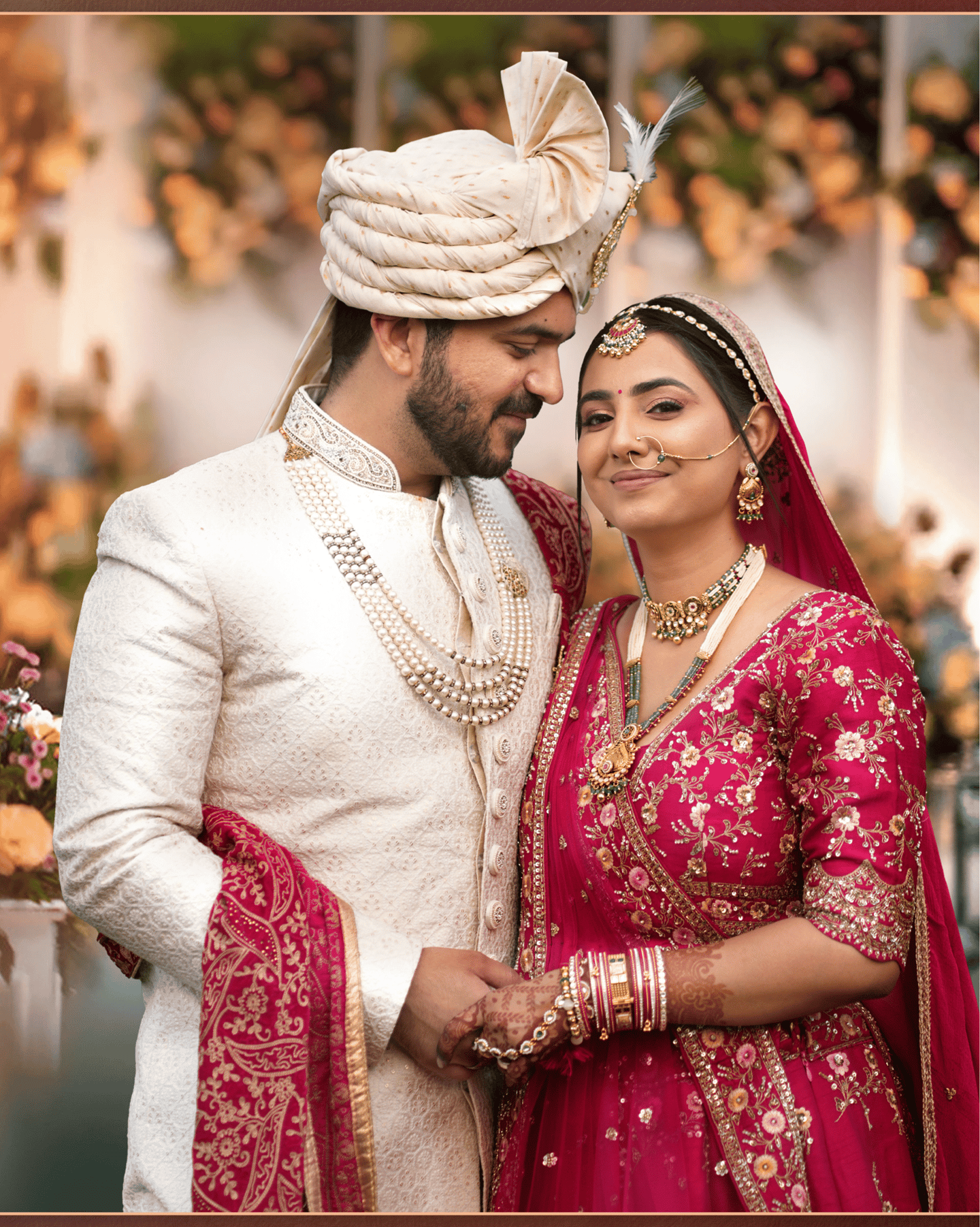 "Traditional Indian wedding photo of a smiling bride in a red and gold embroidered lehenga, & groom