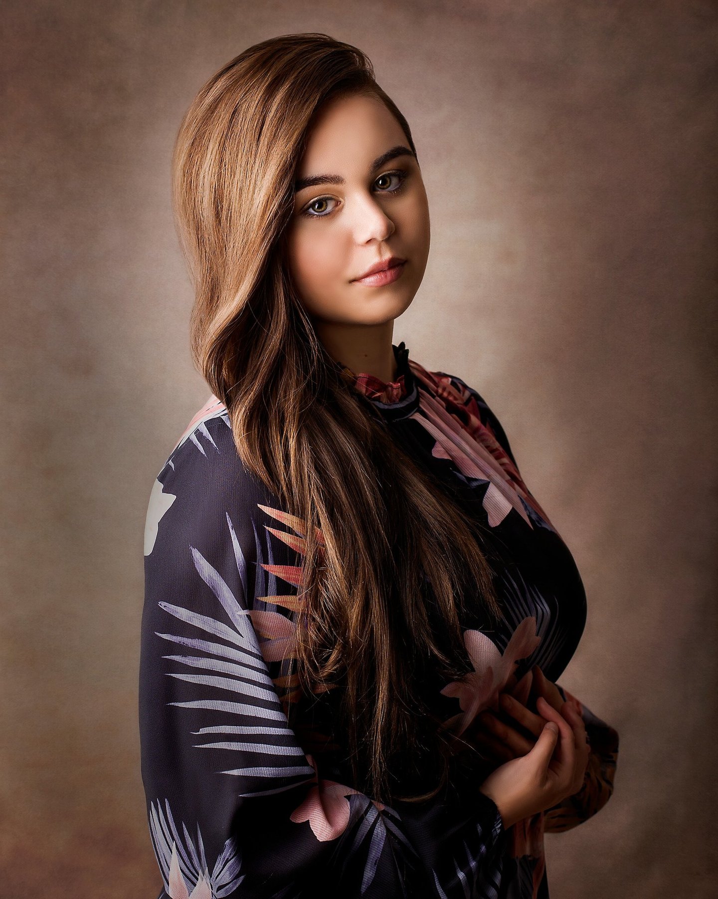 a beautiful girl posing in a photography studio, she has long light brown wavey hair and green eyes
