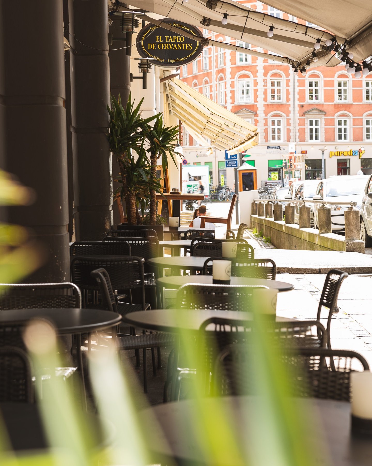 Outdoor sidewalk  at El Tapeo de Cervantes in Copenhagen with black tables and chairs.