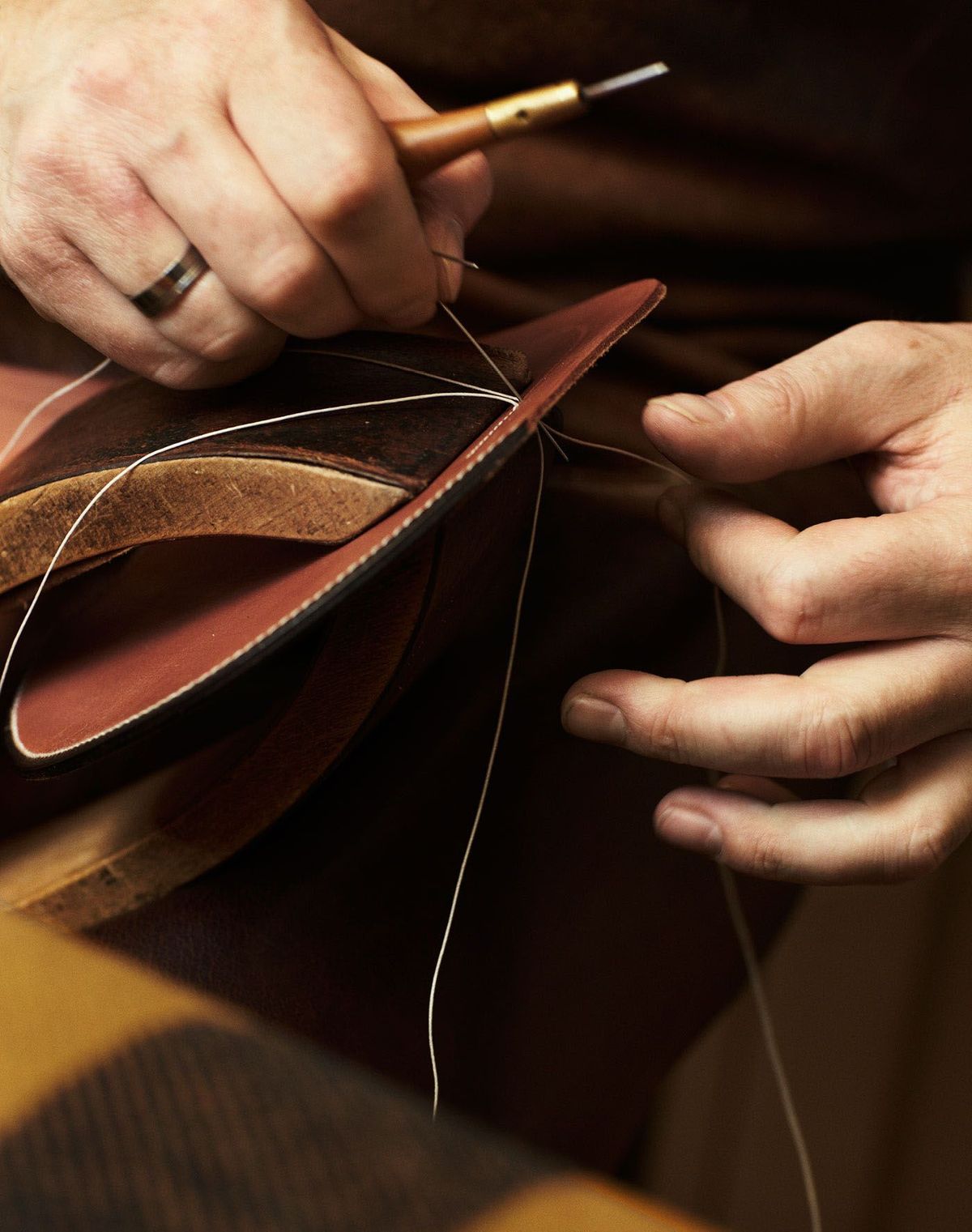 Artisan hand-stitching leather, luxury craftsmanship.