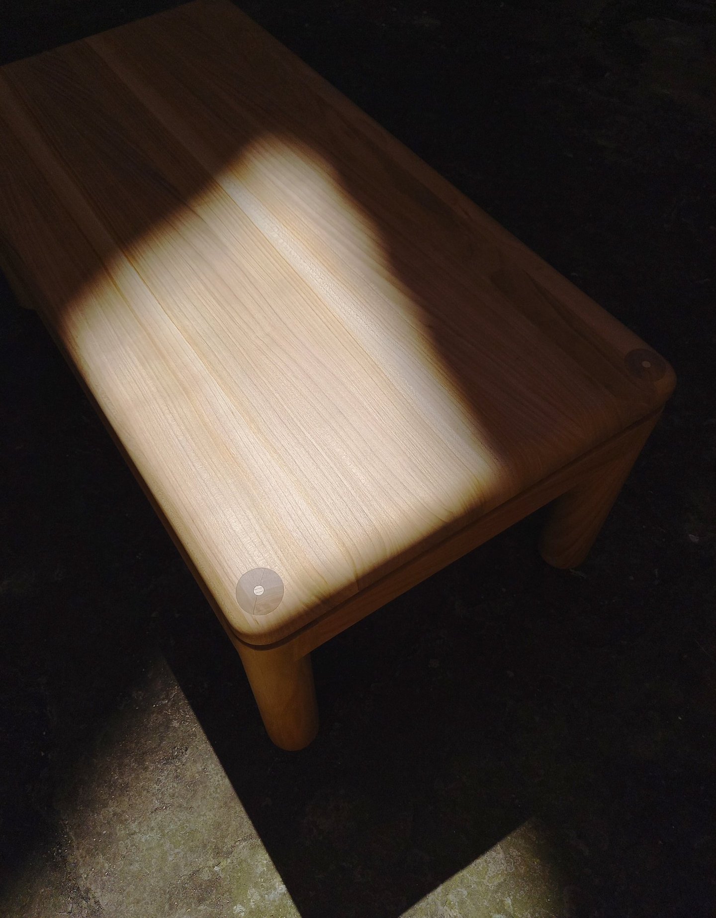 table basse en merisier aux angles et arêtes arrondis dans un rayon de soleil