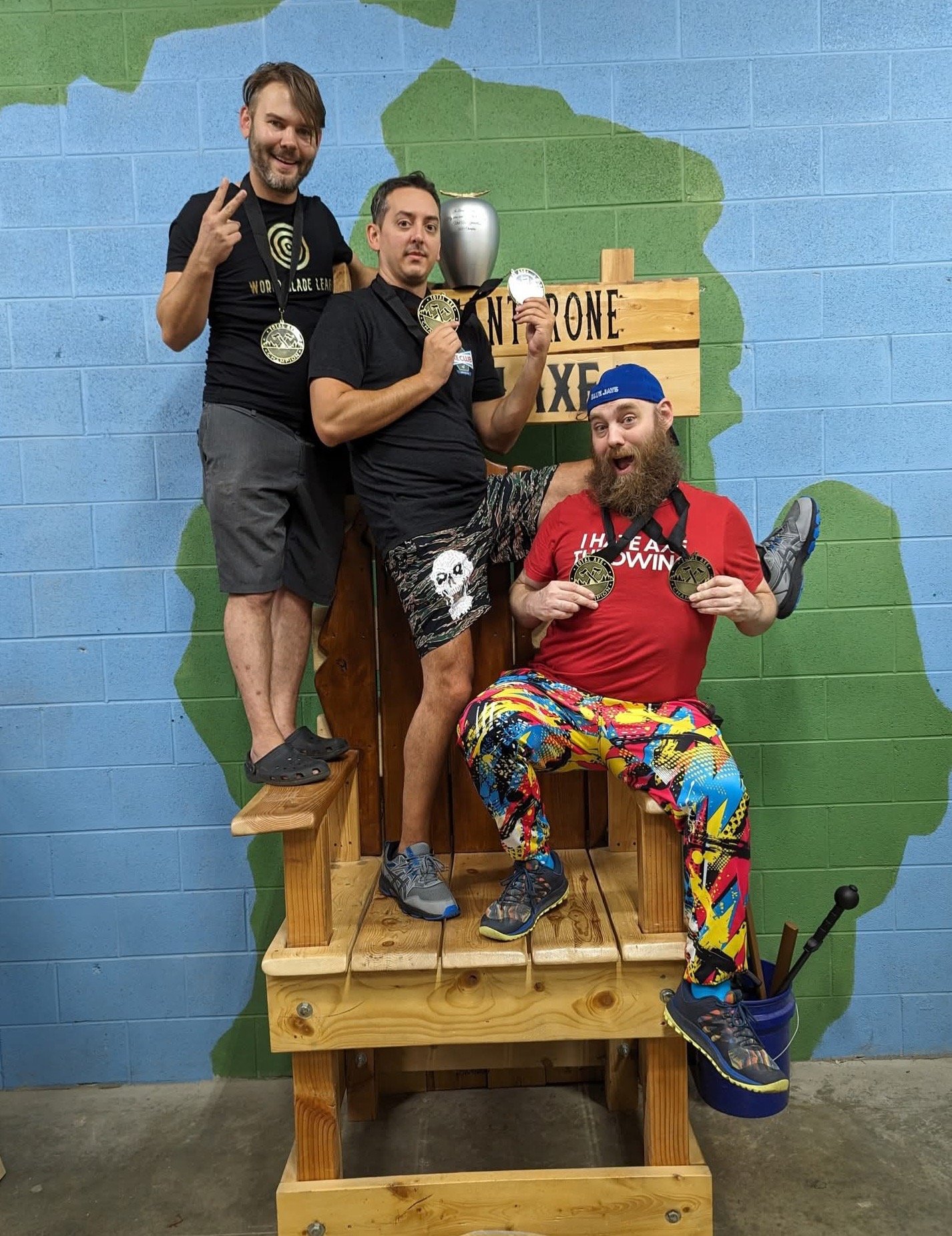 three men showing off their medals standing on a throne