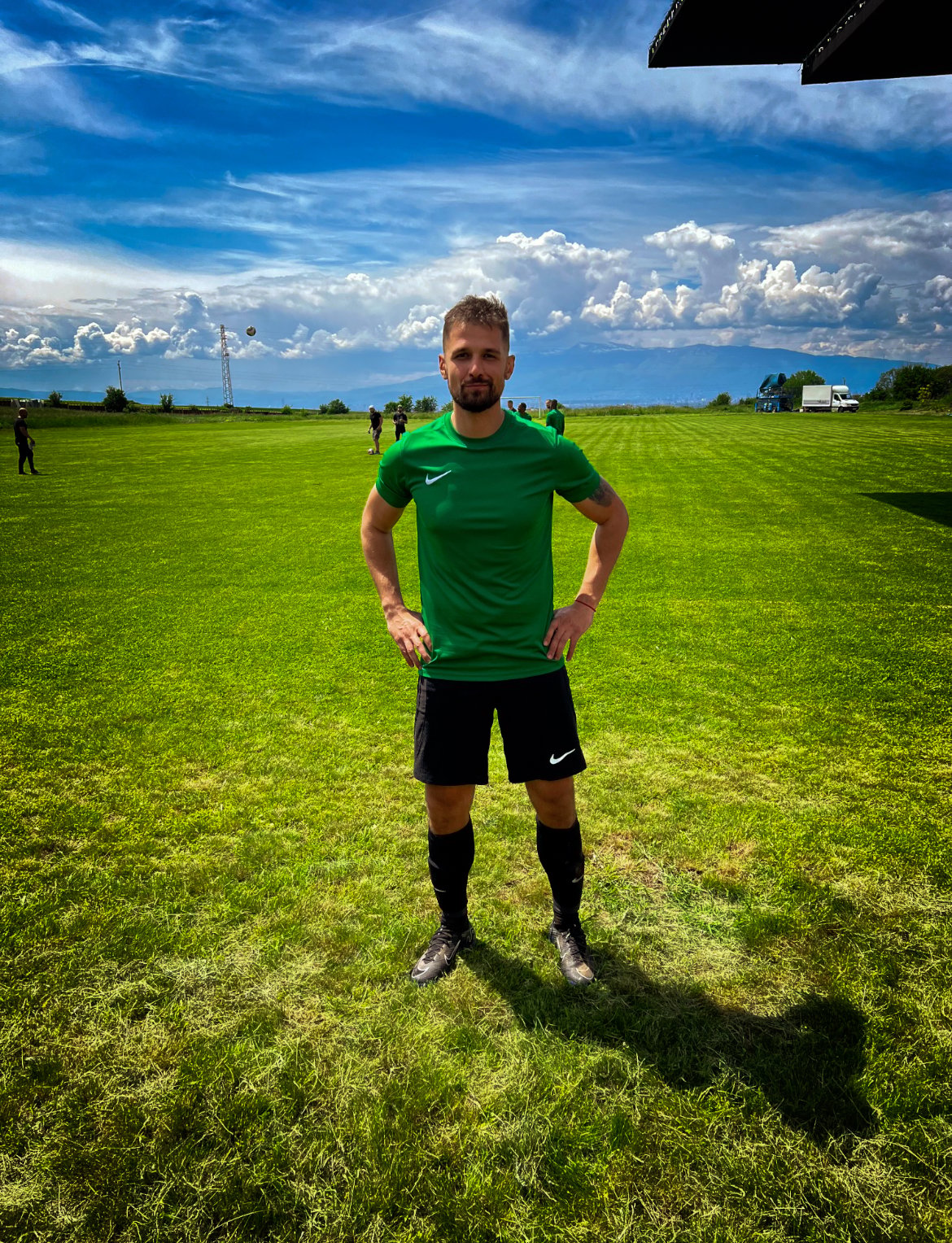 a man in a green shirt and black shorts standing in a field