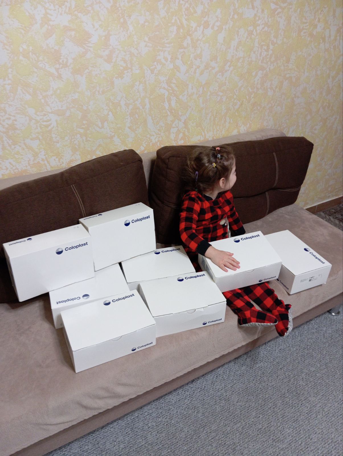 маленька дівчинка сидить на дивані з ящиками коробок