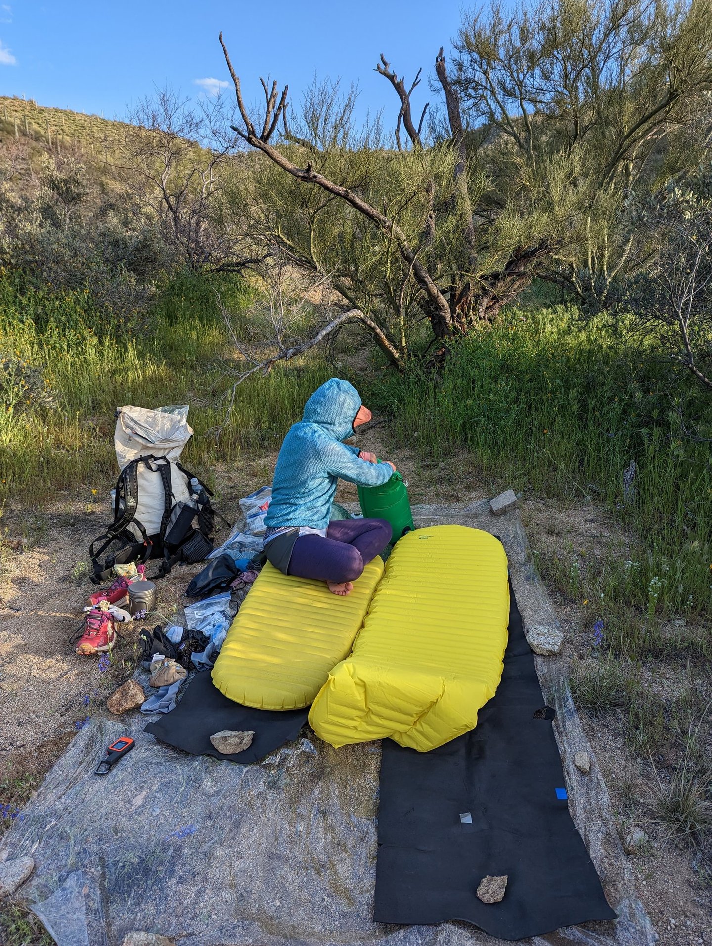 A woman inflating a yellow Therm-a-Rest Neoair sleeping pad in a lush desert canyon in Arizona.