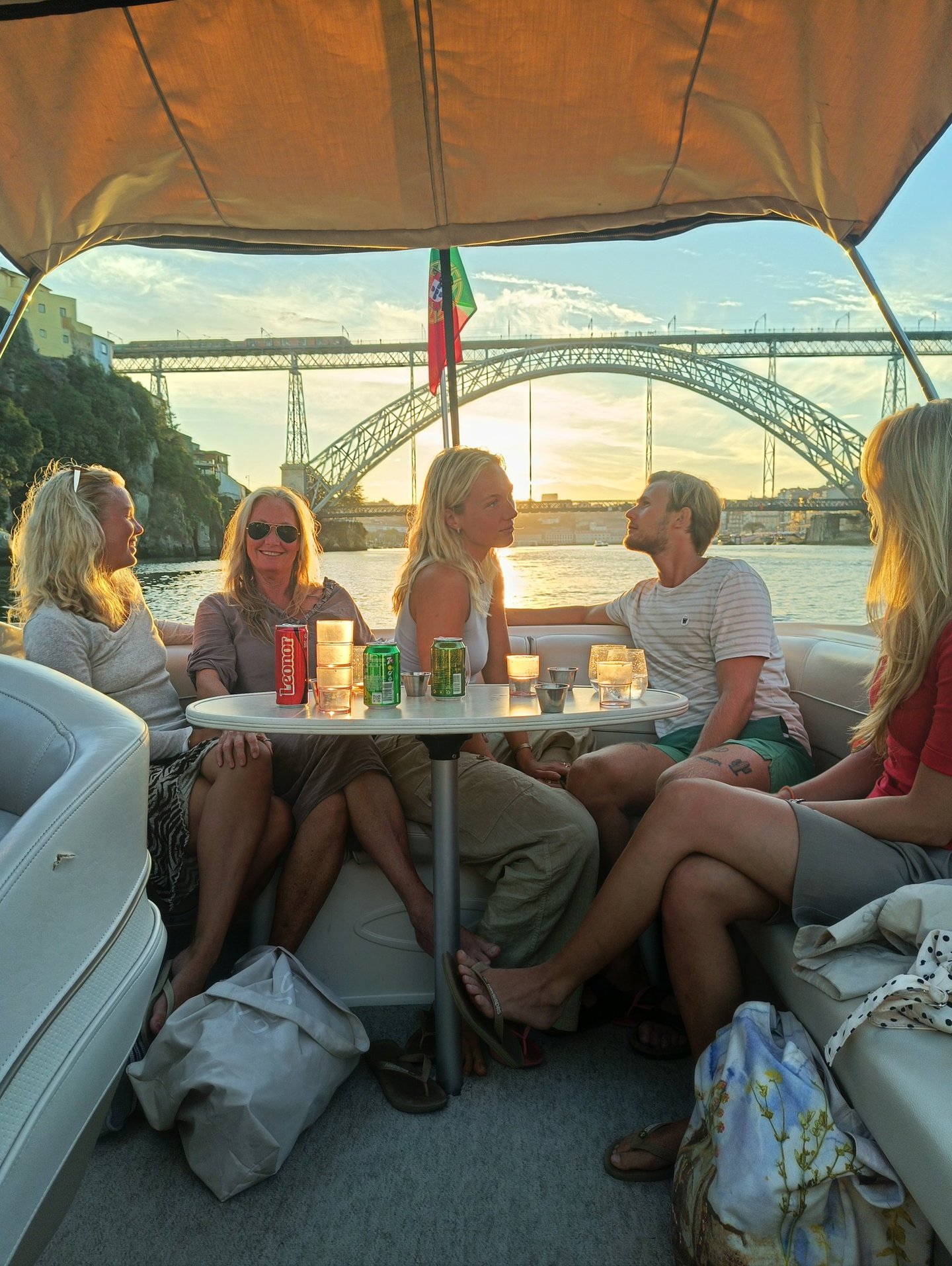 Friends enjoying a sunset boat tour in Porto with views of the Dom Luís I Bridge.