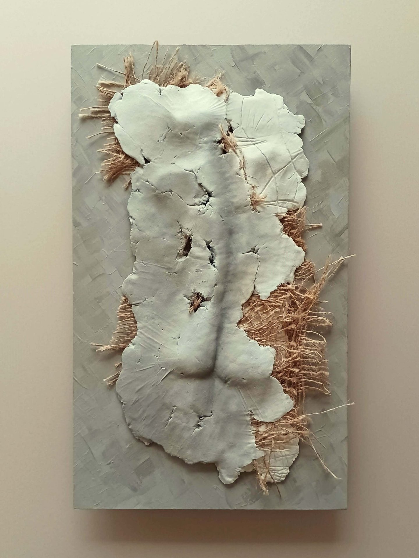 A relief sculpture of a fragmented female (rear view) with protruding hessian, painted cool browns