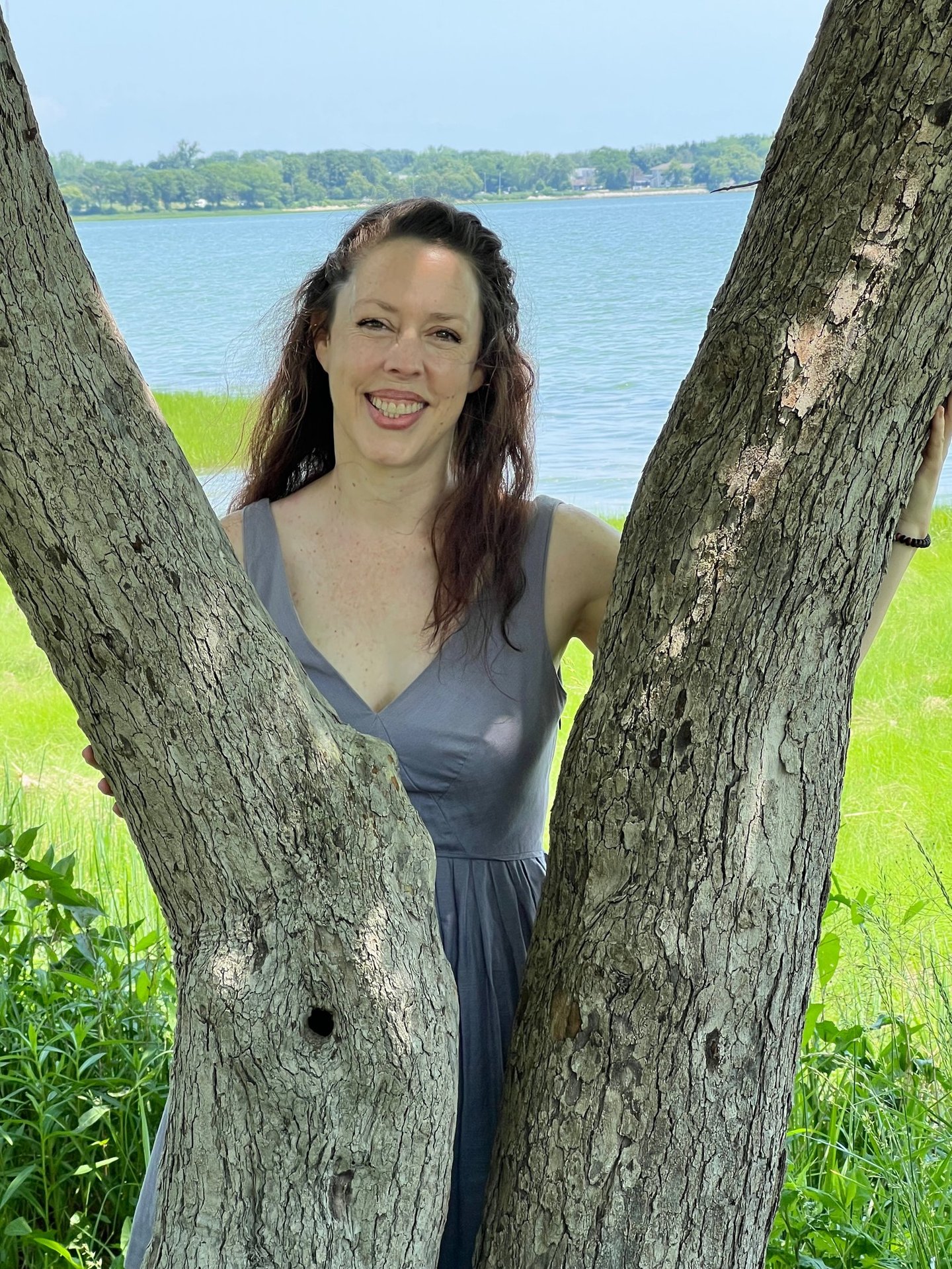 a woman in a dress standing in front of a tree