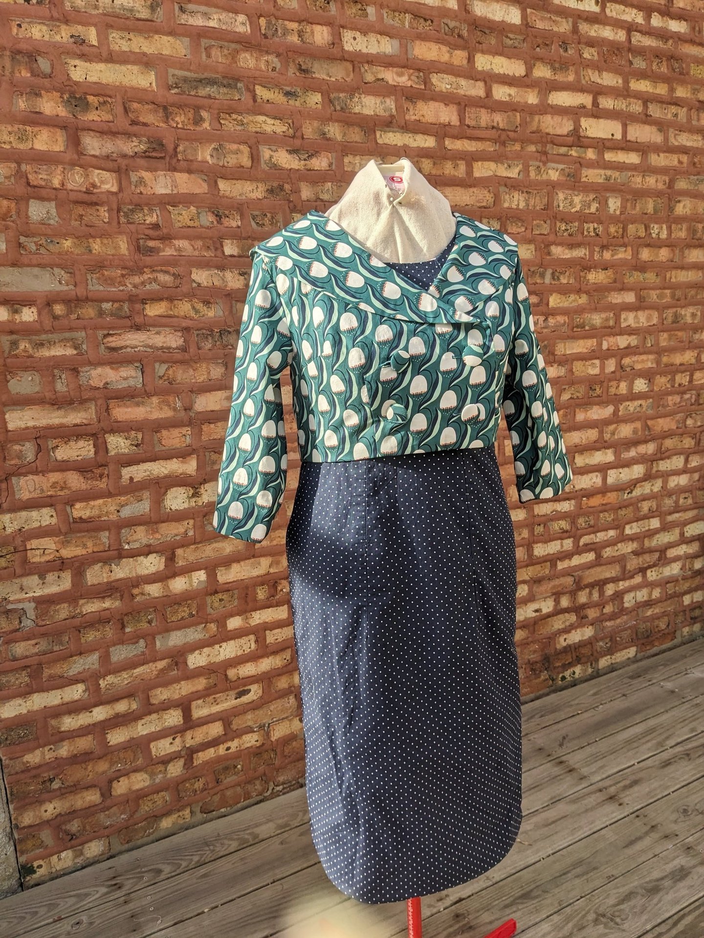 The front of a navy polka dot reversible sheath dress and green 50's inspired jacket