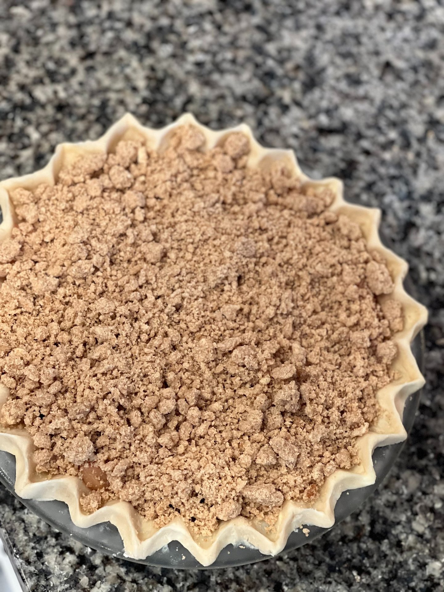 Freshly baked homemade apple crumble pie with a decorative fluted crust and buttery streusel topping.