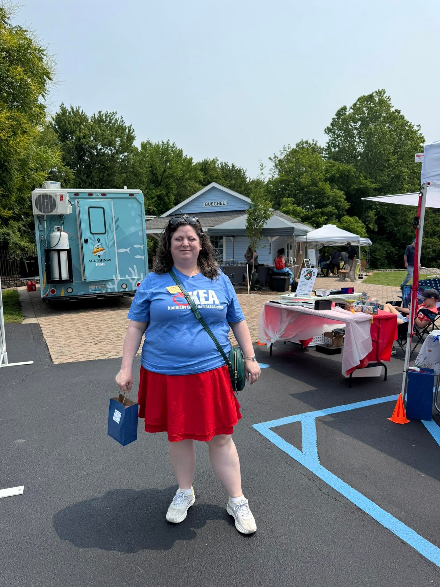 Woman in KEA tshirt standing in front of booths at the public library cultural pass kickoff