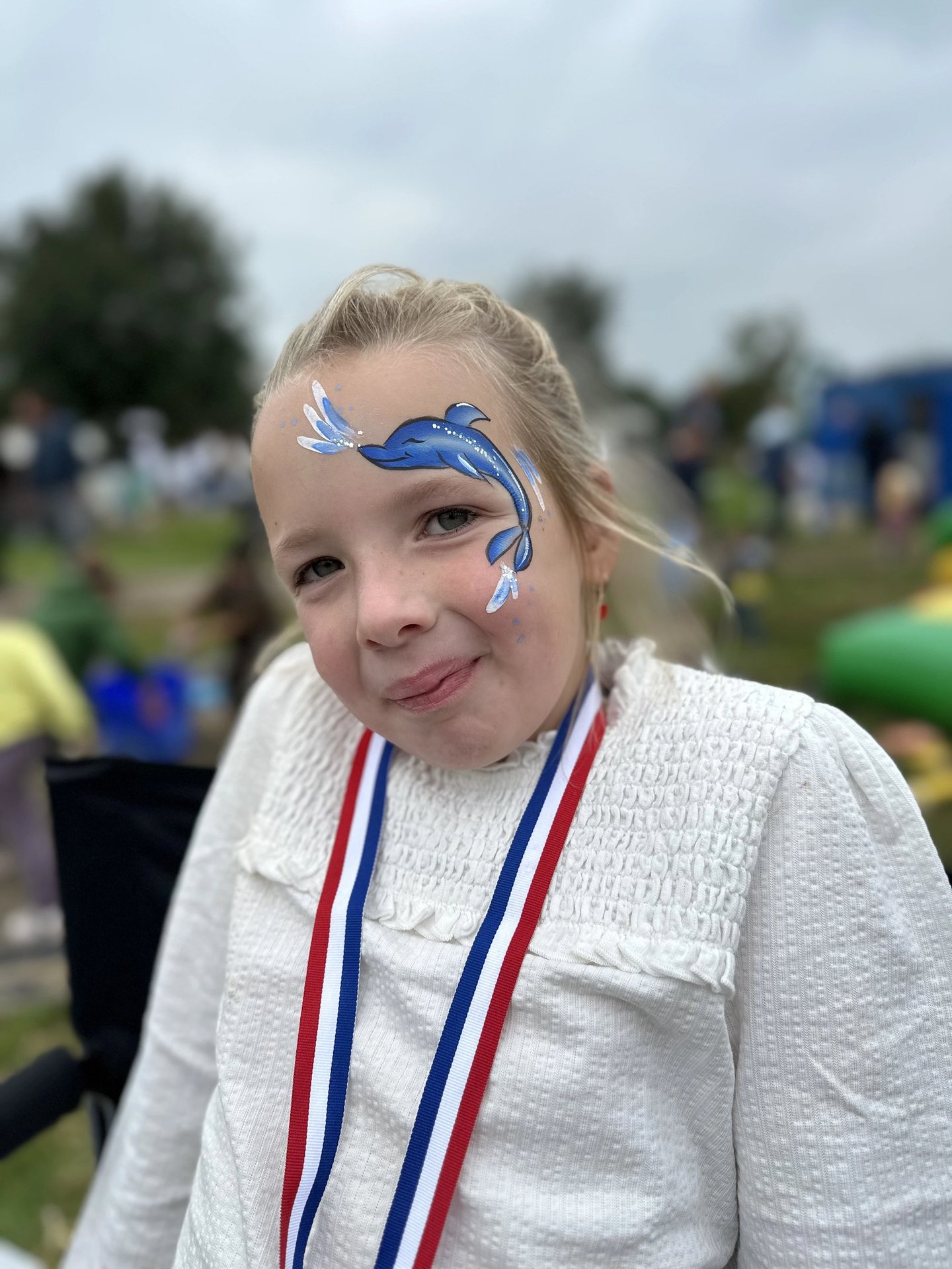 Meisje met een gedetailleerde blauwe dolfijn op haar gezicht geschminkt.