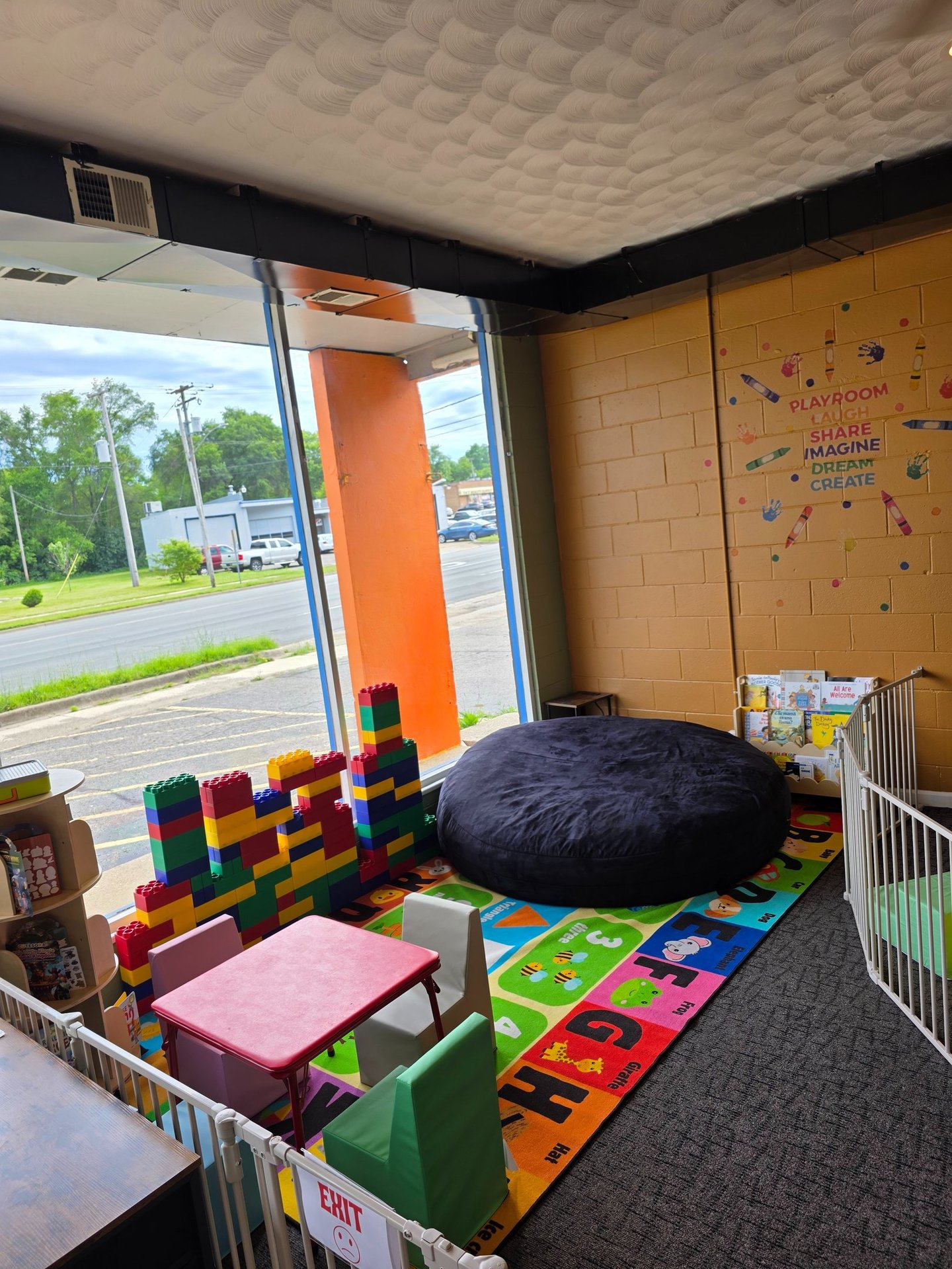 Indoor children's playroom with colorful alphabet mat, giant bean bag, and oversized building blocks.