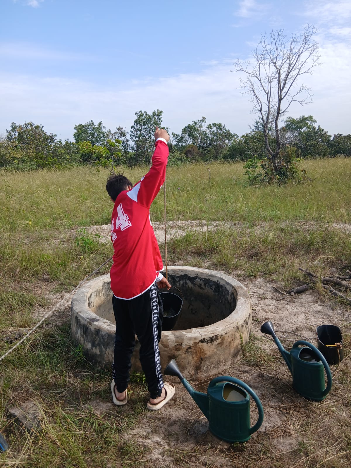 Photo d'un jeune accompagné par Bourokk et Kadiamor qui cherche l'eau dans le puit