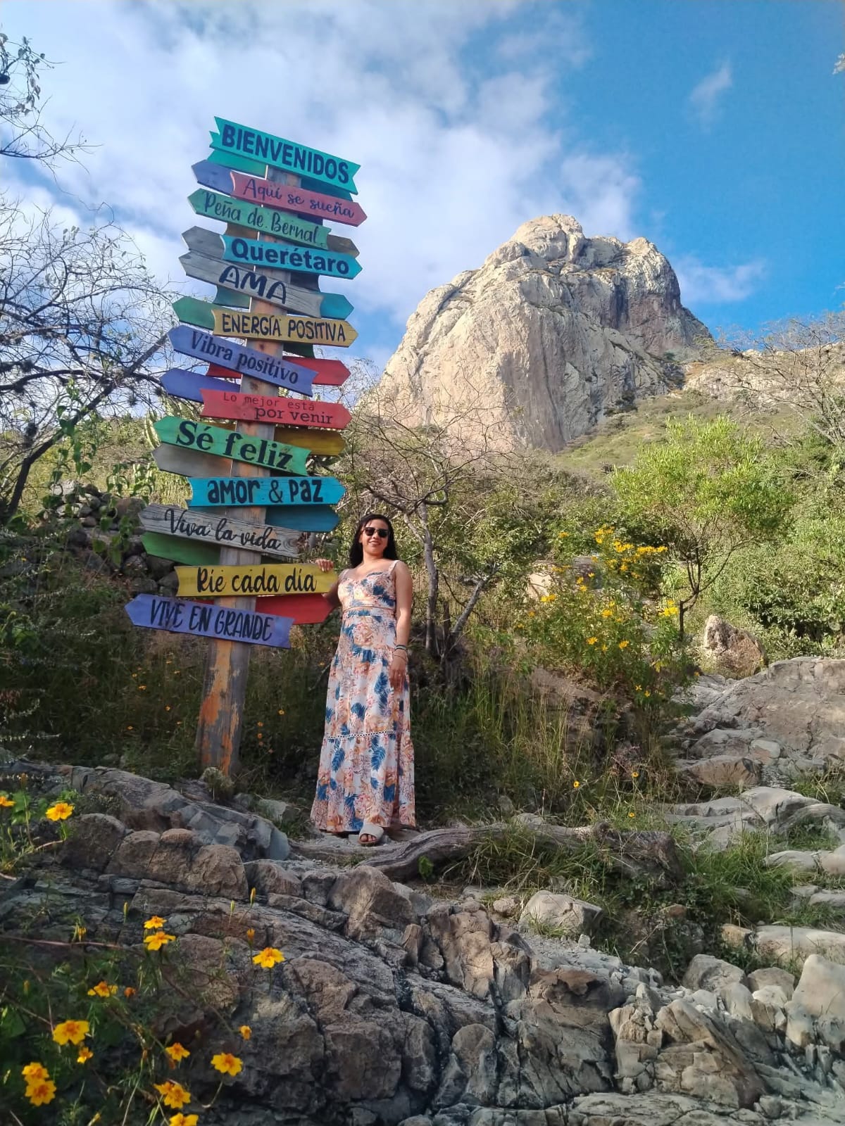 mujer en la peña de bernal posando en letreros direccionales