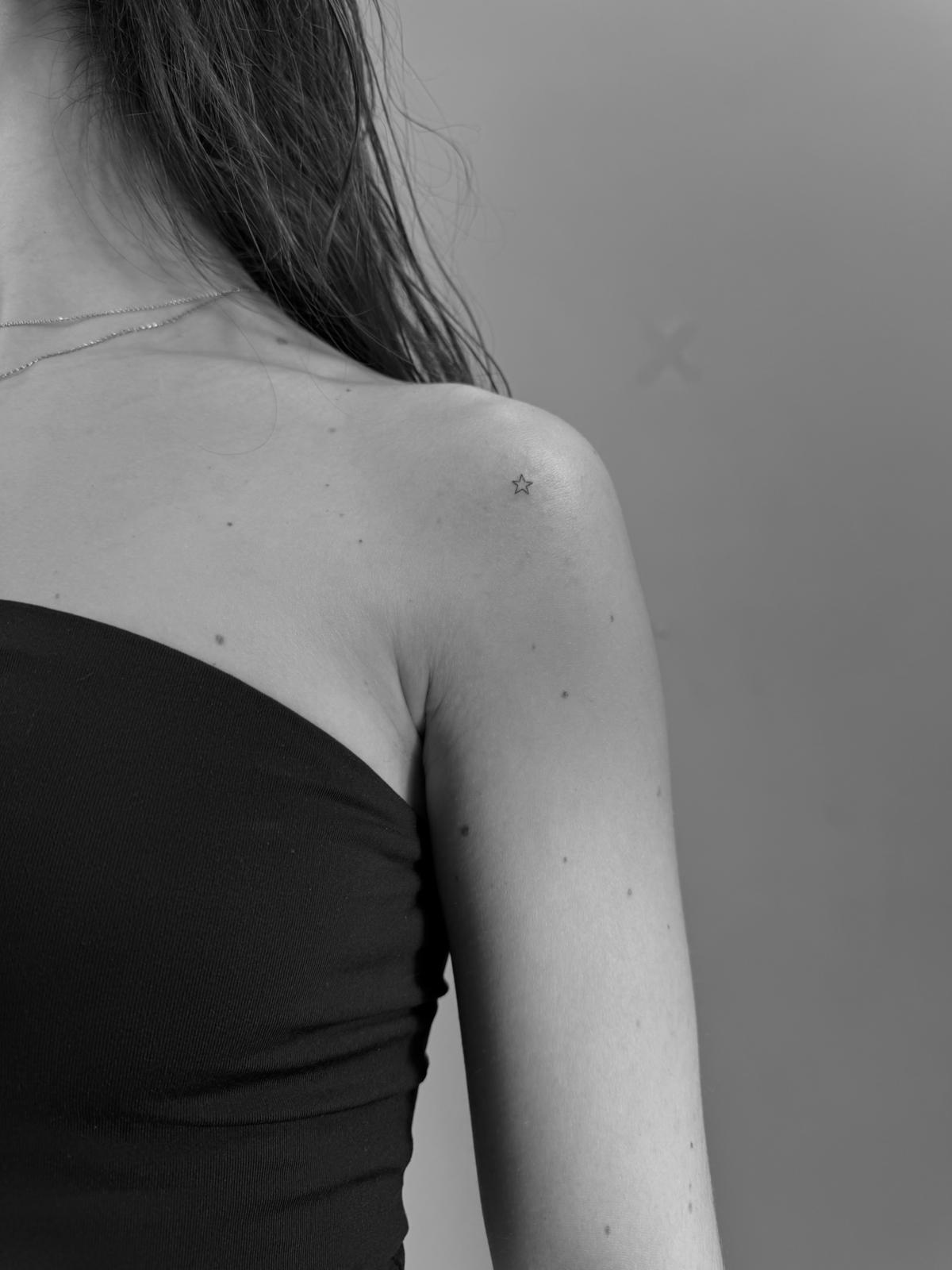 Tatuaje fineline en Madrid de estrella micro minimalista en trazo muy fino en el hombro