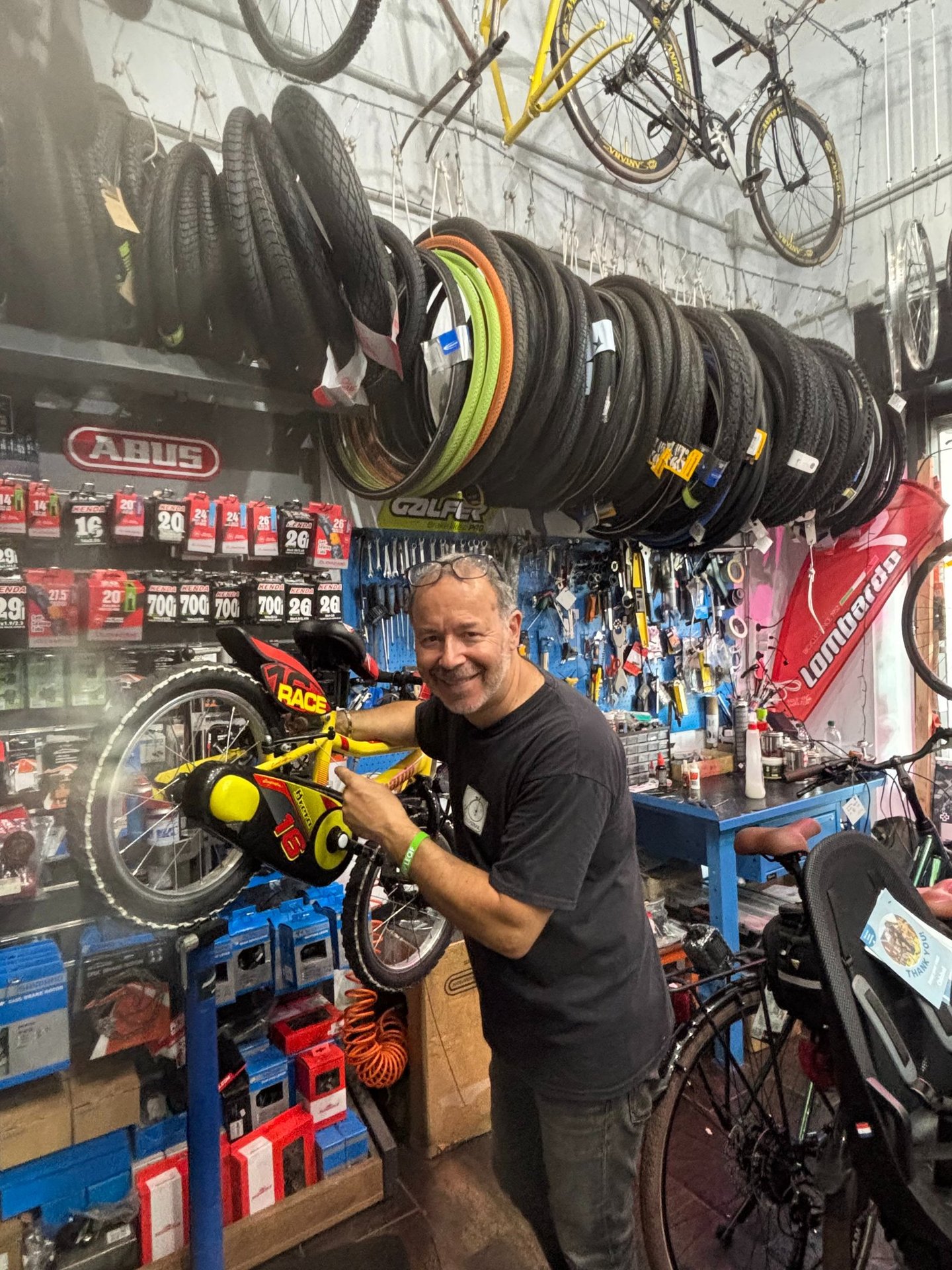 Federico, il proprietario di abicicomeprima, sorride intento ad aggiustare una bici da bambino