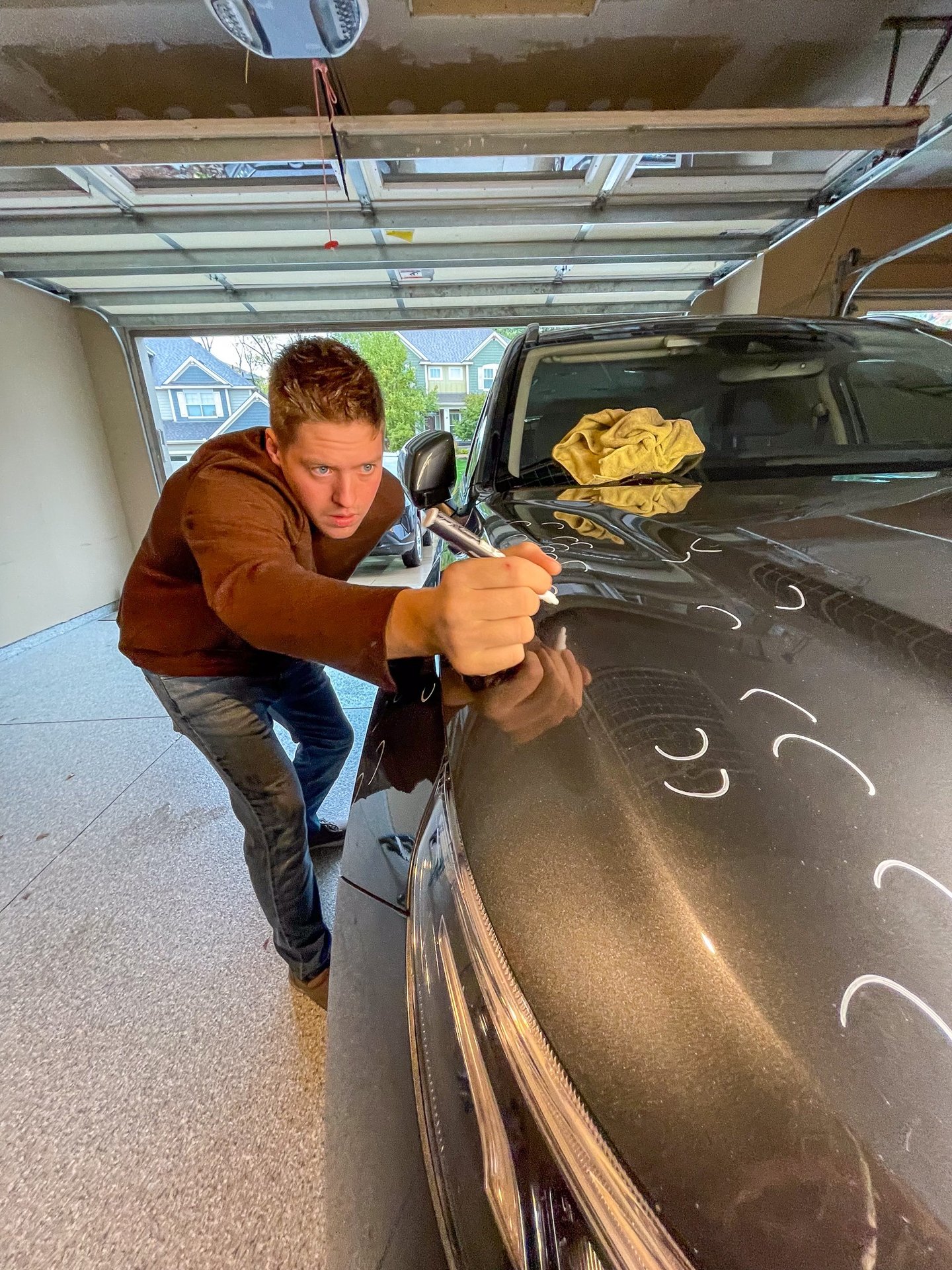 PDR tech marking hail on a hood of a gray SUV vehicle.