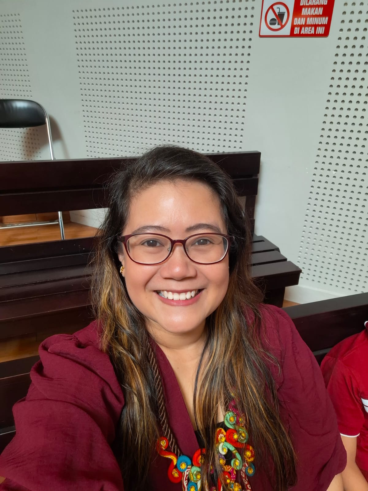 a woman in a red shirt and glasses sitting at a table
