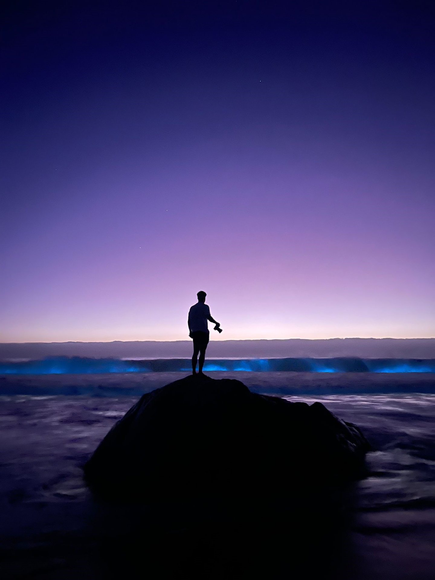a person standing on a rock in the ocean