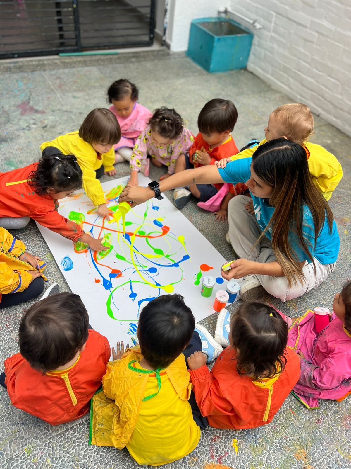 Niños con pinturas brillantes jugando sentados en el piso