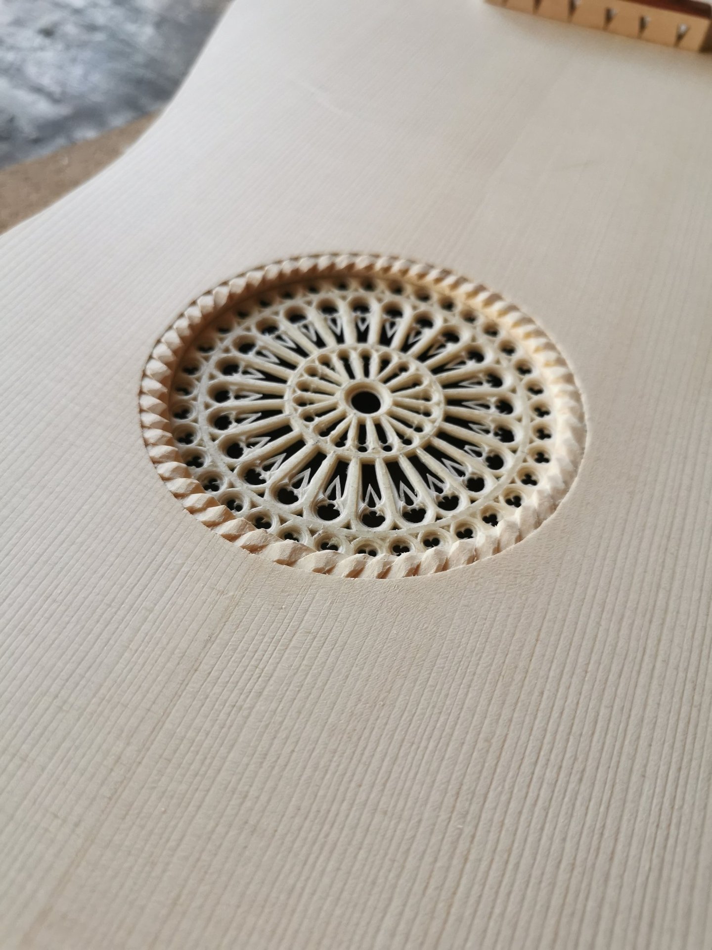 Close-up of an intricate hand-carved rosette covering the soundhole of a Renaissance vihuela