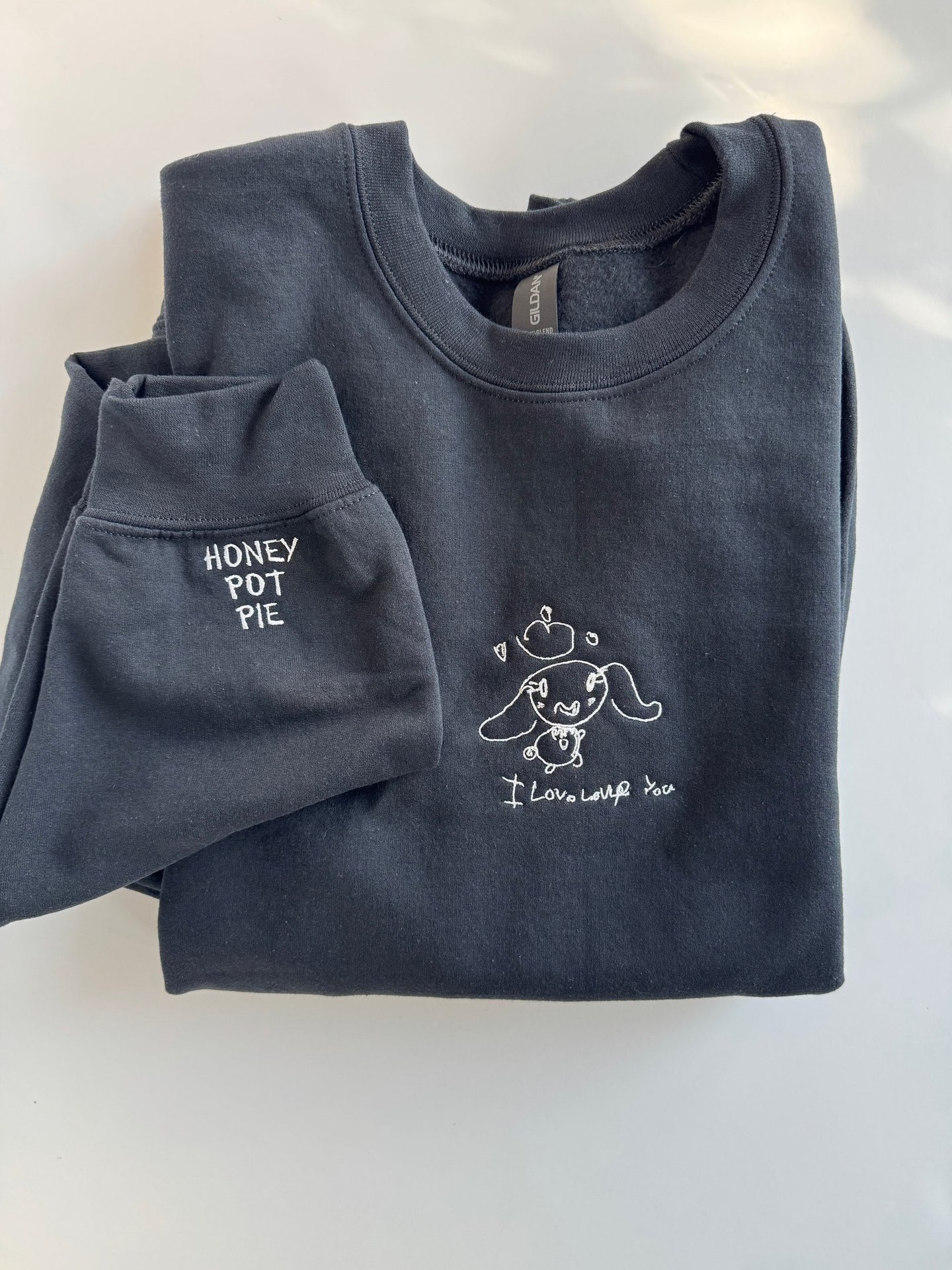 a black sweatshirt with a child's drawing embroidered on it