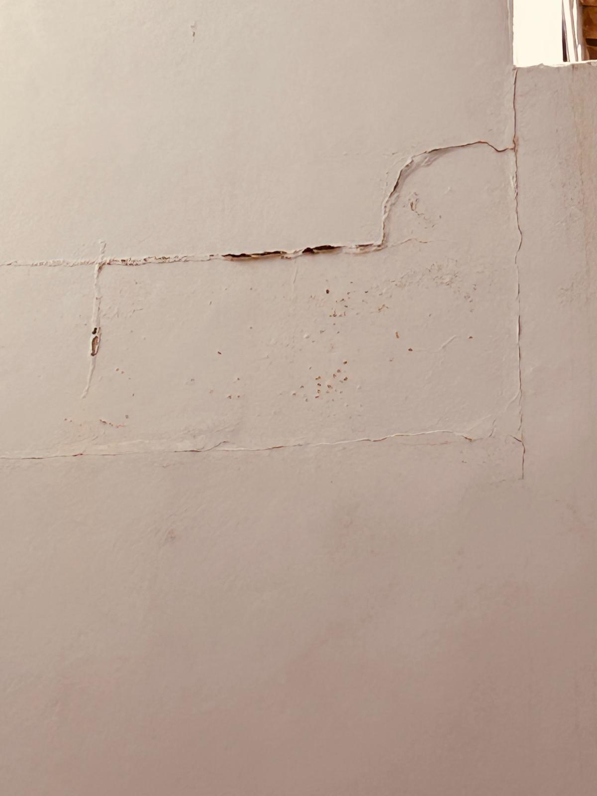 Visible cracks and water damage on a white interior wall requiring drywall repair.