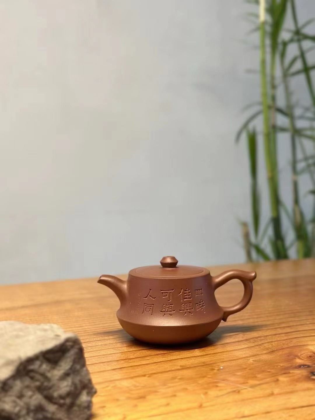Teapot engraved with characters placed on a wooden table