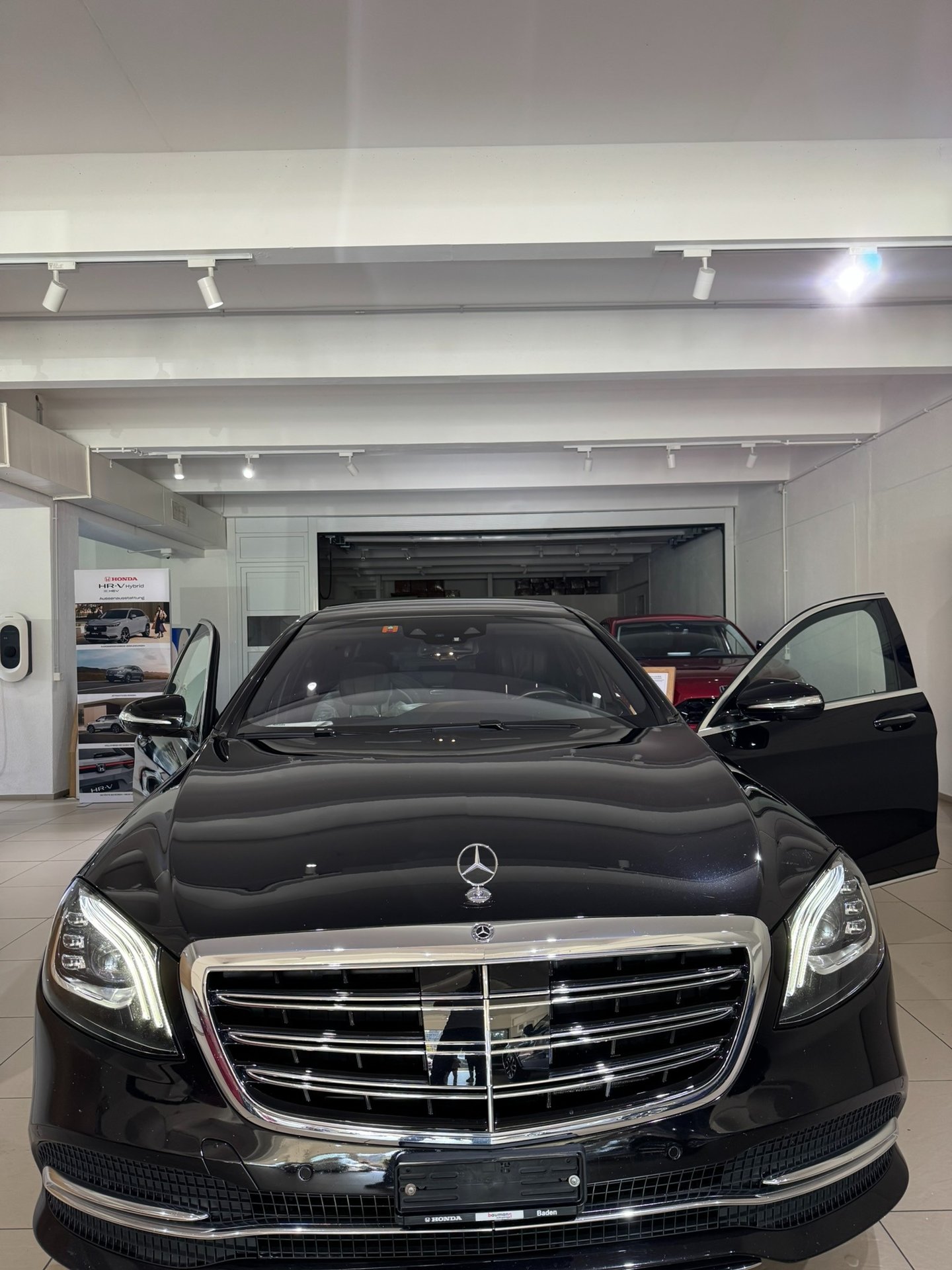 Black Mercedes S-Class with open doors in the hall of a carselling Store