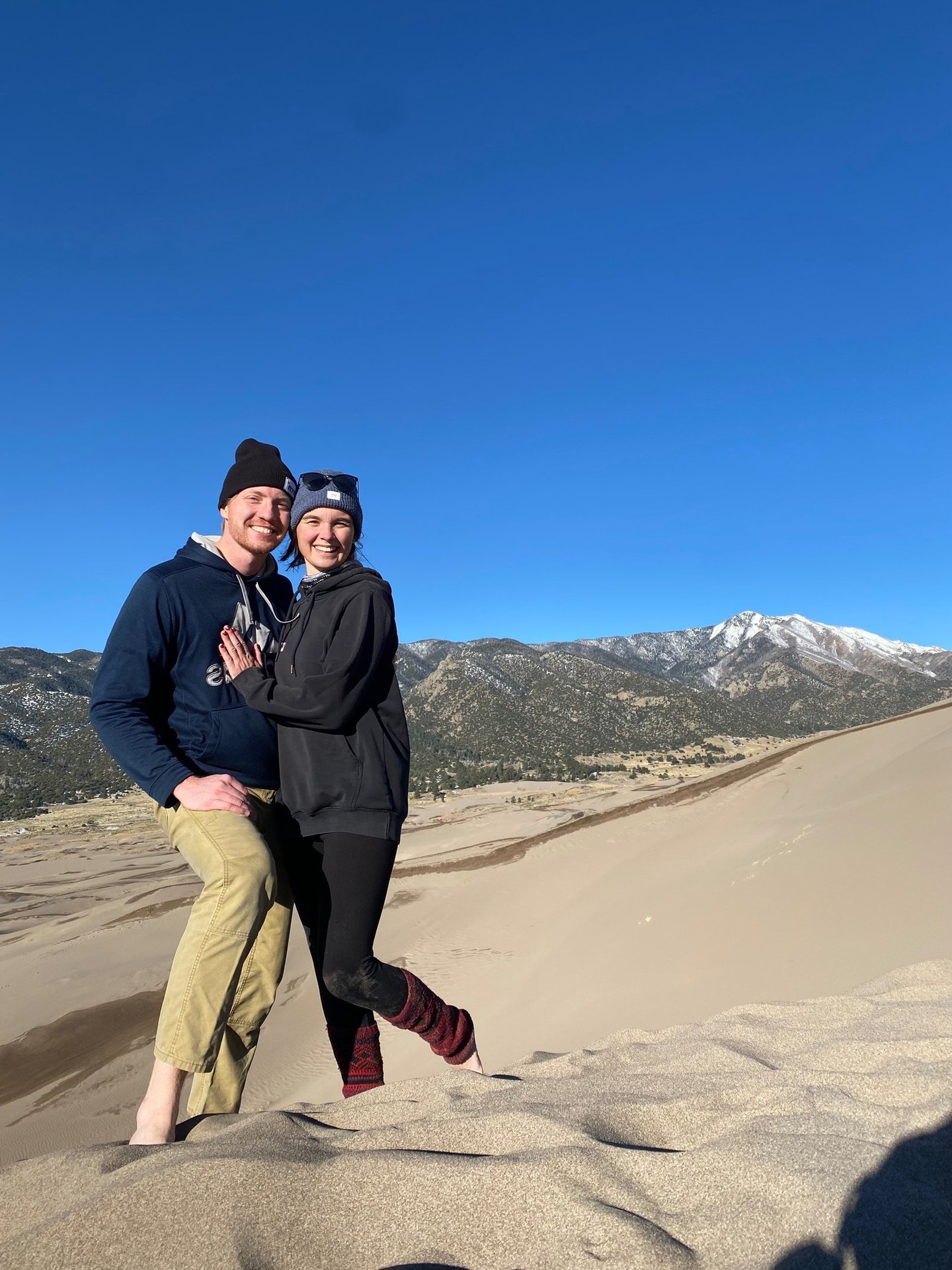 Alex and Nick smiling together on the sand dunes at Great Sand Dunes National Park
