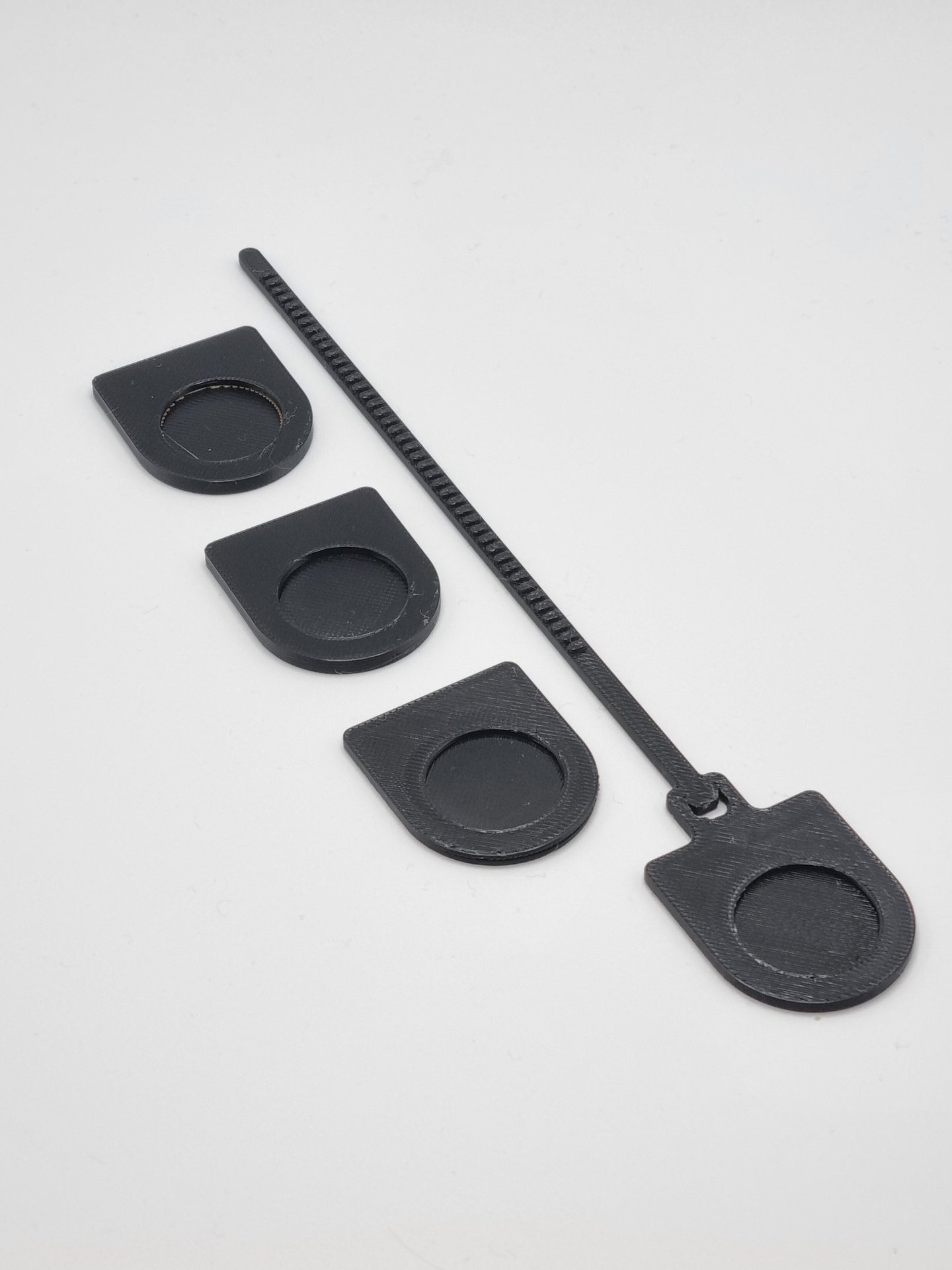 Black 3D printed cable management clips and a zip tie style organizer on a white background.