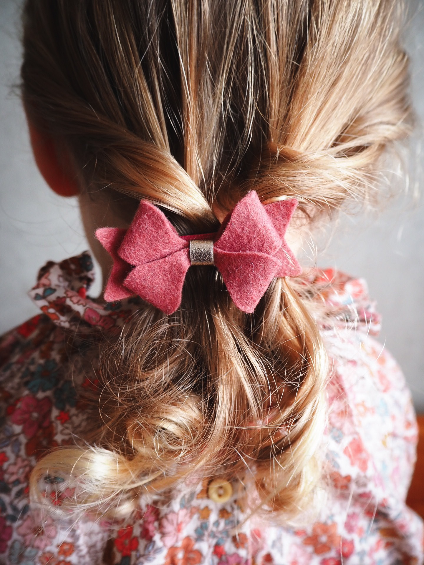 kokarda z koralowego filcu zapięta na włosach dziewczynki z jasnymi włosami