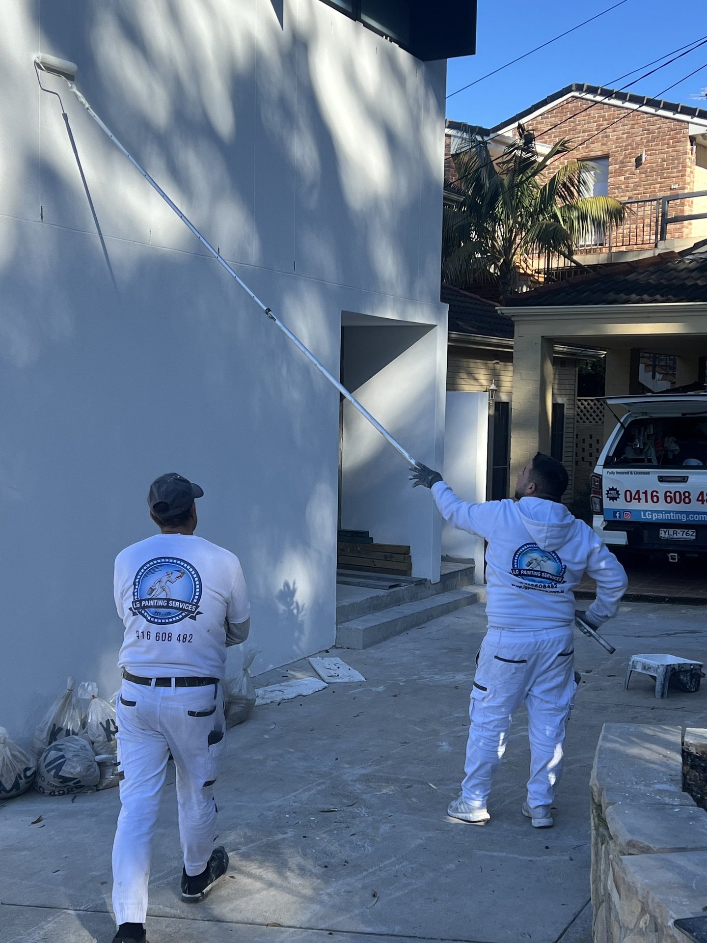 LG painting Servises in white suits and white shirts are painting a wall