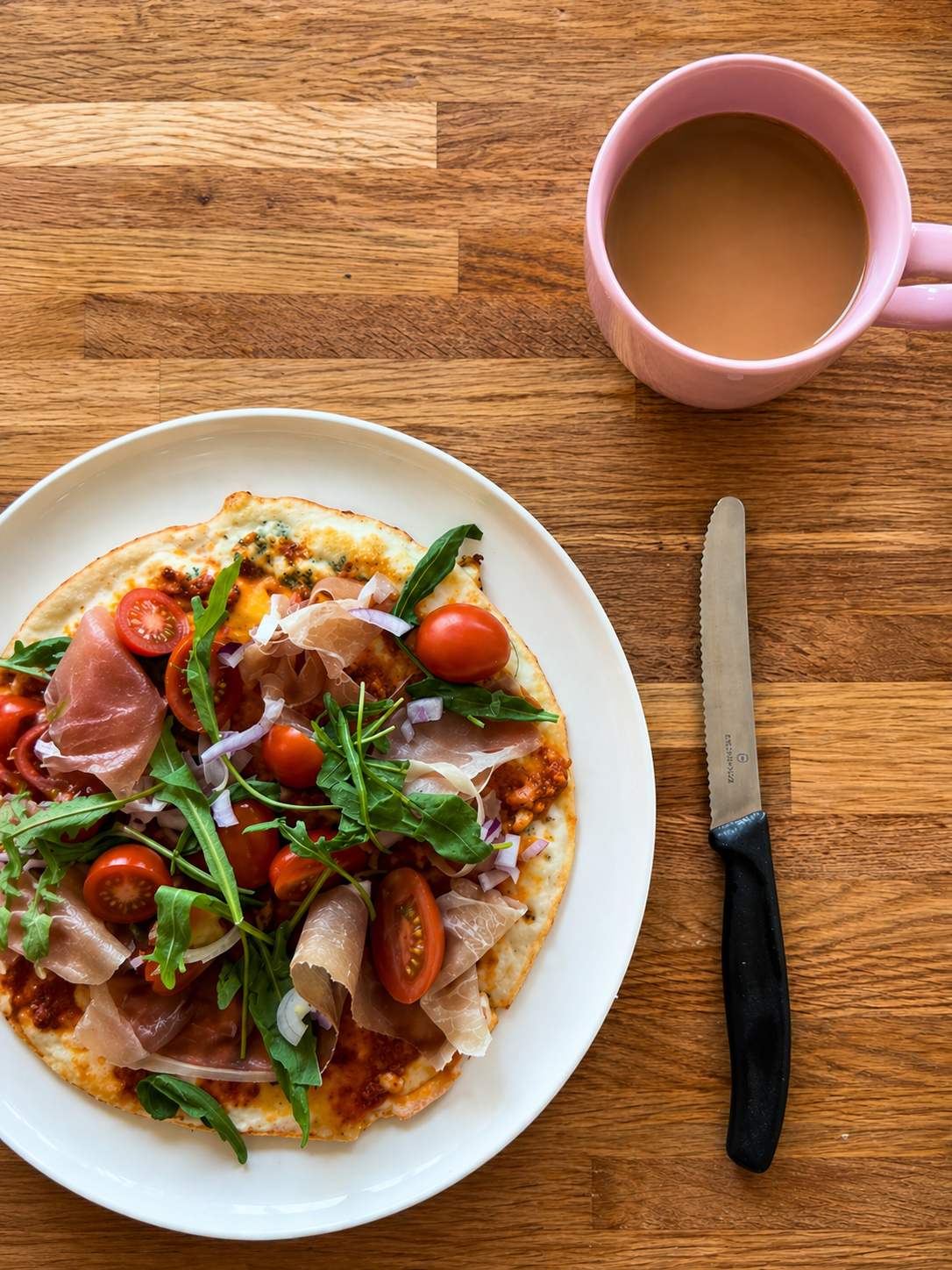 High protein breakfast egg pancake with prosciutto, cherry tomatoes, arugula and melted cheese serve